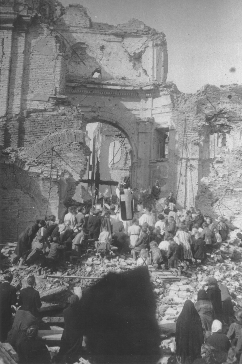 A priest conducts mass among the ruins of the Franciscan convent on Zakroczymska Street in Warsaw where Jewish children were hidden during the German occupation.

The inscription on the back of the photograph reads, "There are more than 1,000 dead buried beneath the rubble."