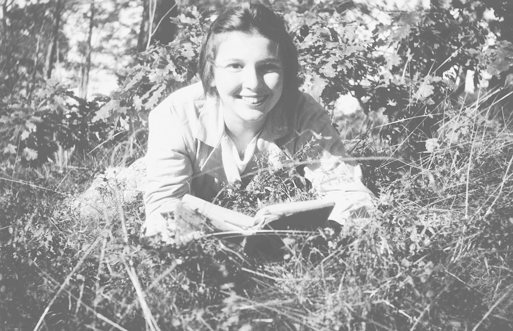 Helga Arndtheim reads in the grass at a convalescent home in Sweden.   On the back of the photo, she says in German "To my beloved Aunt Paula from her niece Helga."