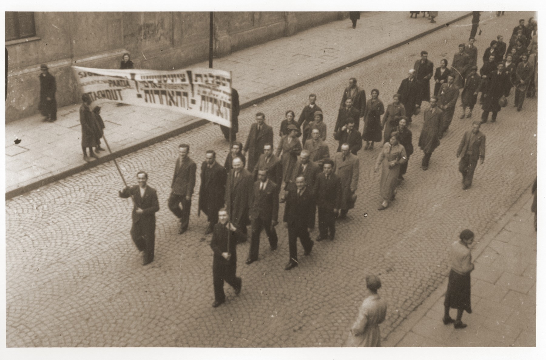 Labor Zionists march behind a large banner in a May Day parade in Warsaw.