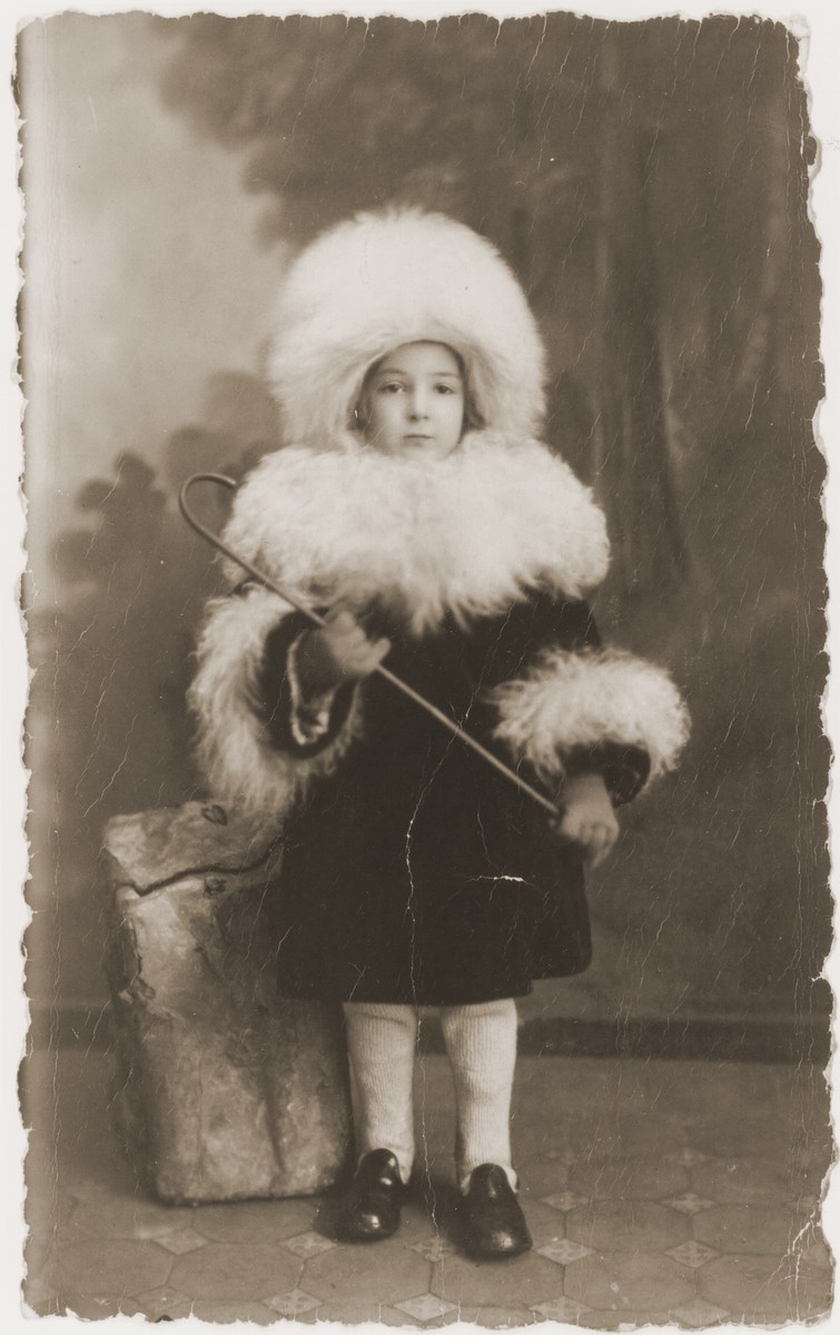 Studio portrait of a Jewish child from Warsaw dressed up in a fur hat and collar.

Pictured is Rivka Radzinski.