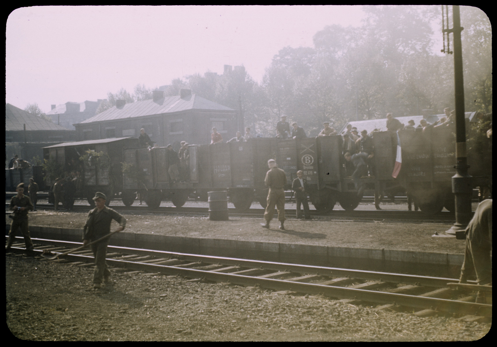 Displaced persons (?) transported by rail car, with military personnel in the foreground.