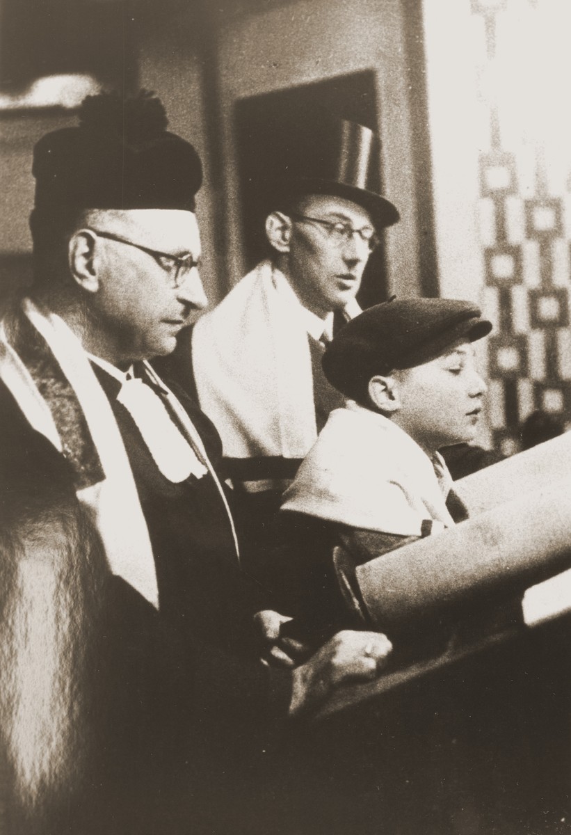 Siegbert Levy, flanked by his father (right) and Cantor Hermann Levy, reads from the Torah scroll during his bar mitzvah at the liberal Zerrennerstrasse synagogue in Pforzheim.