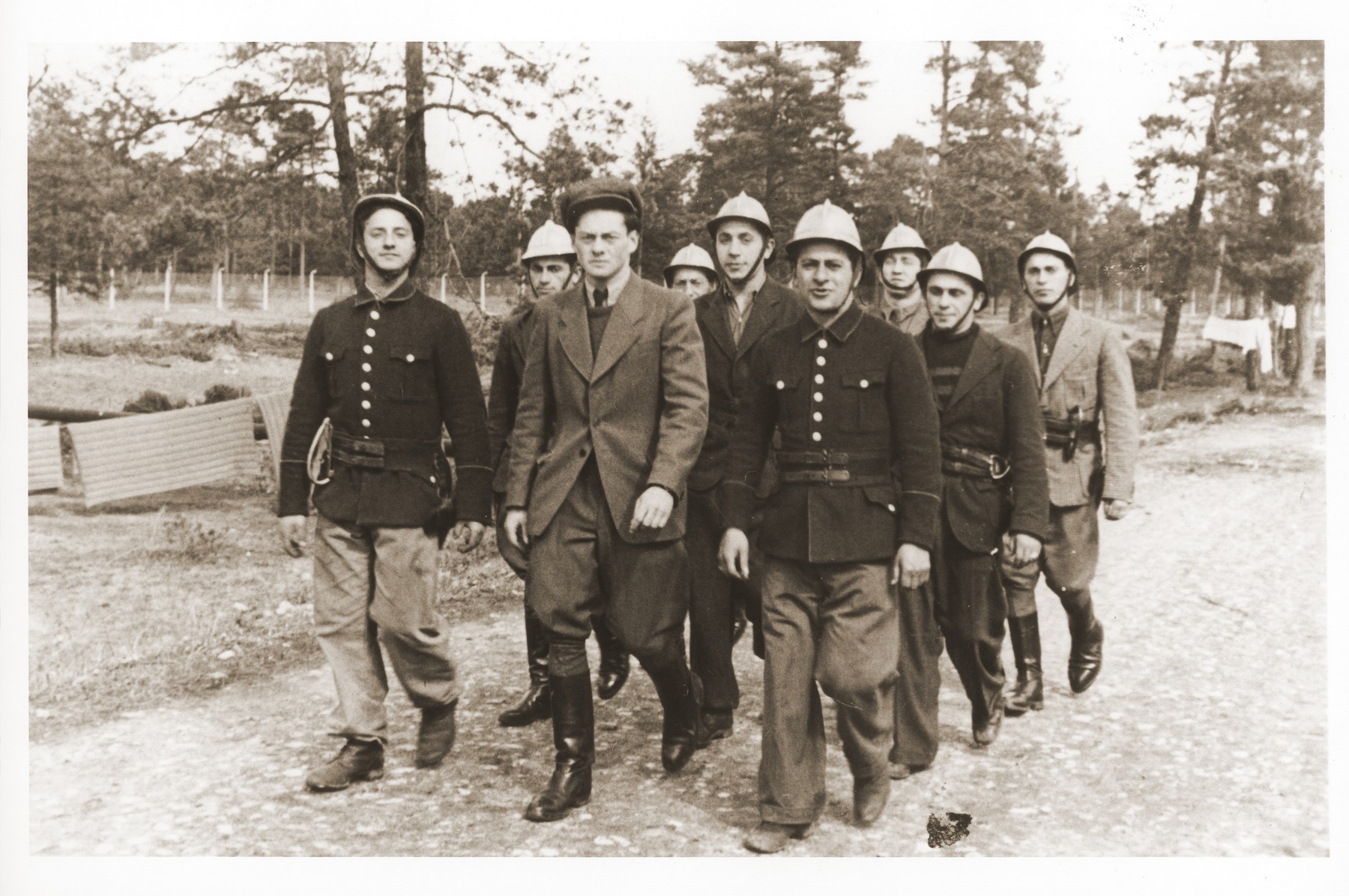 Members of the Foehrenwald displaced persons camp fire department march along a road in the camp.

Oskar Littman, the fire chief, is pictured in the center wearing a soft cap.  Sol Zeifman is pictured in the back, far left.