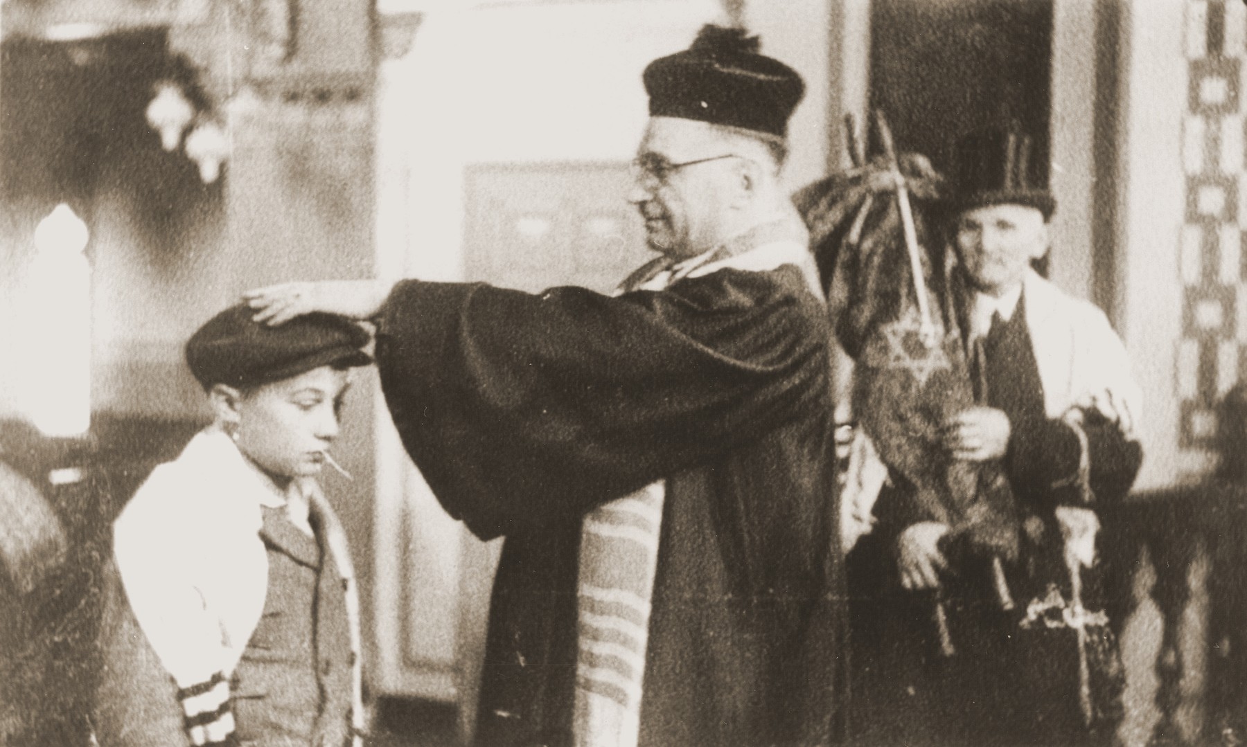 At the liberal Zerrennerstrasse synagogue in Pforzheim, Cantor Hermann Levy blesses Siegbert Levy during his bar mitzvah, while Siegbert's great-uncle (holding the Torah scroll) looks on.
