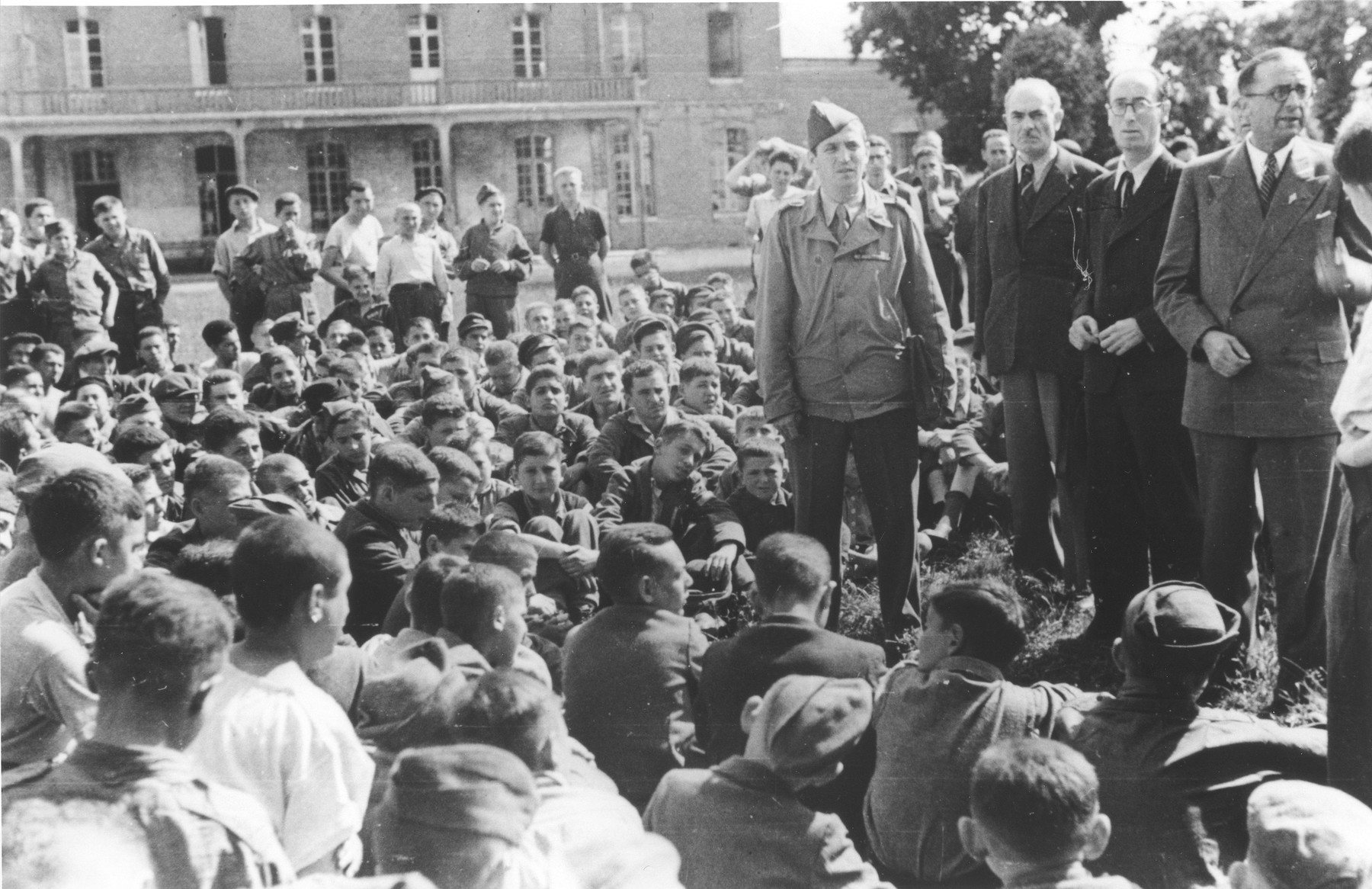 Jewish youth who were members of the Buchenwald children's transport listen to Colonel Rozen and representatives of the OSE at an outdoor meeting at the Ecouis children's home.