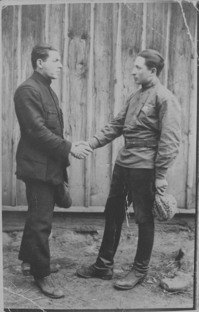 Two friends shake hands in front of a wooden wall.

Naftali Berkowitch is on the right and Israel Pogarelski on the left.  Naftali immigrated to Palestine.