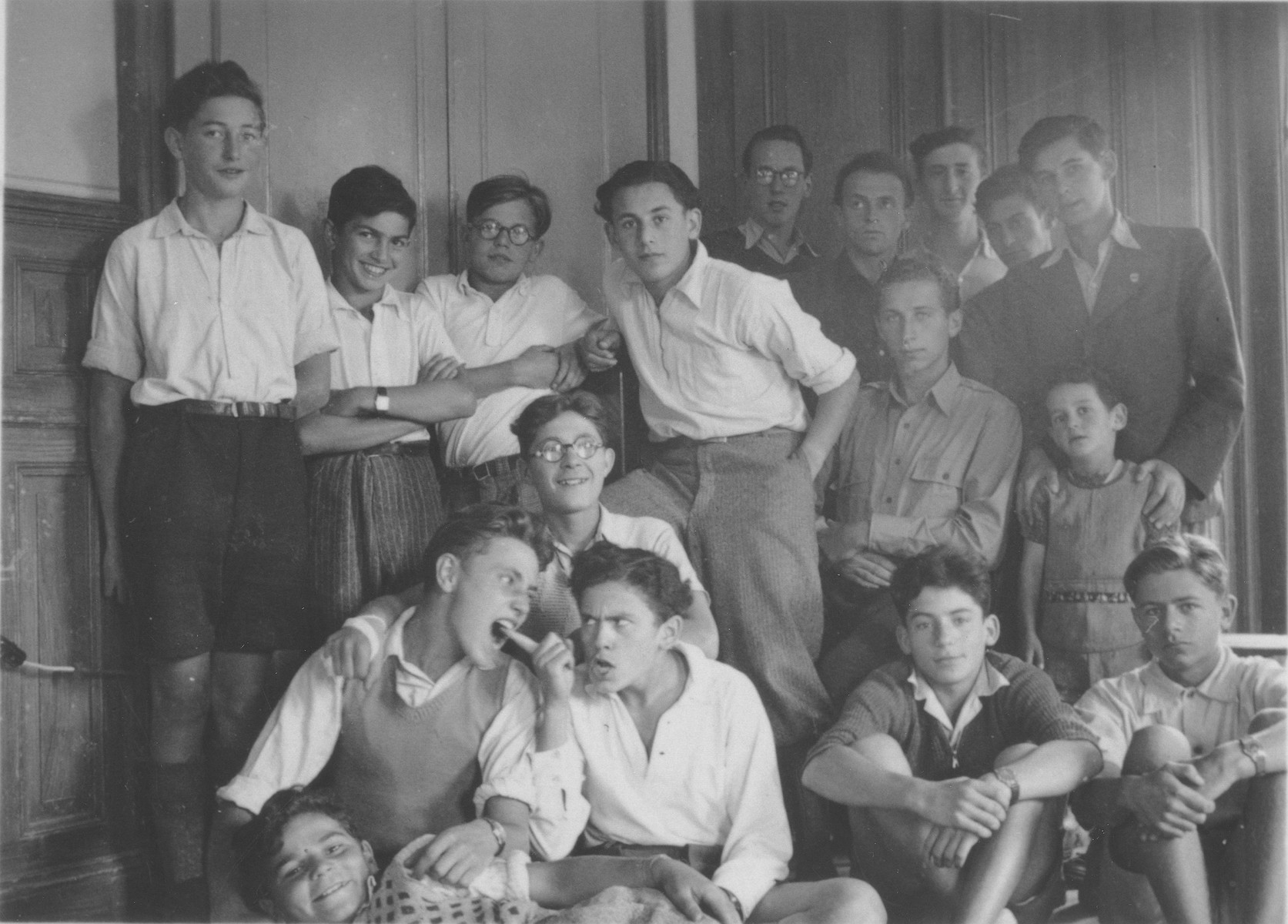 Group portrait of Jewish refugee boys in the Hôme de la Forêt, a children's home run by the OSE (Oeuvre de Secours aux Enfants) in Geneva, Switzerland.

Among those pictured are Victor Grasztok (in the center with glasses), Paul Kornowski (front row, far left, biting the finger of his friend), Gilles Segal (front row, second from left), Norbert Bikales (front row, far right?), Gert Silver (back row, far left), and Henri Samuel Kornowski (back row,) and Rudolph (back row, second from the left).  The boy standing with glasses is Bibi. Lying in the very front is Isidor Menache,"Bouboul."
