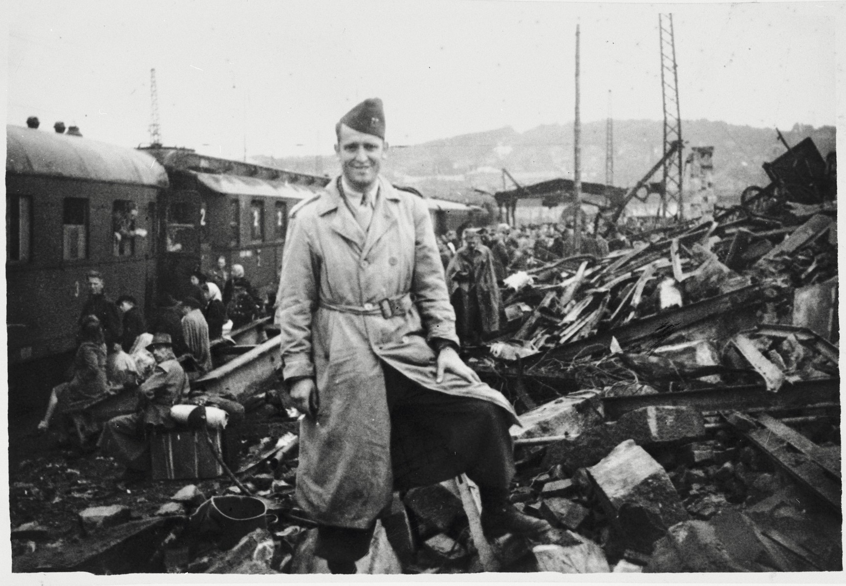An American soldier poses next to a huge pile of rubble alongside a railroad after the war.