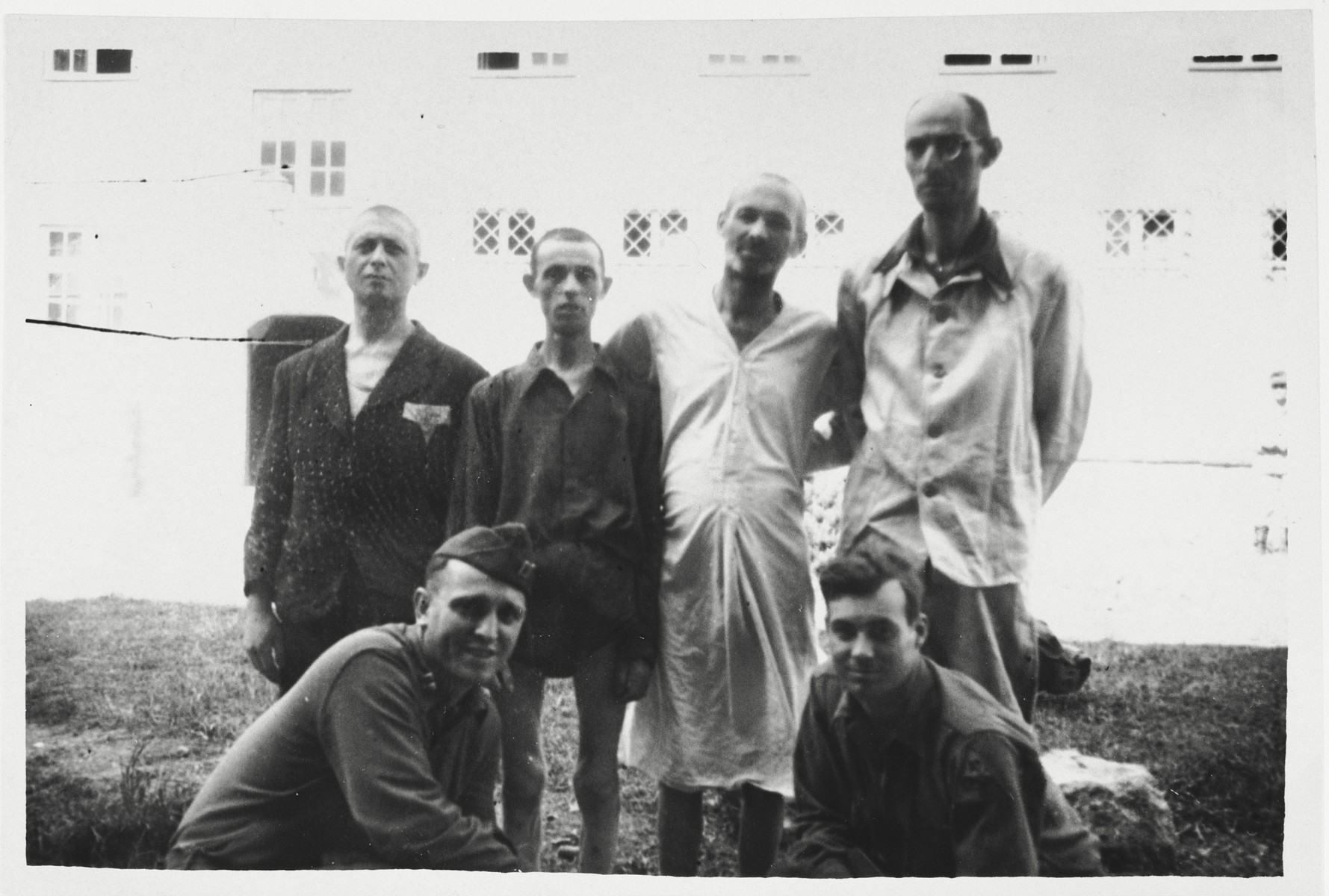 Four survivors of Dachau and Buchenwald pose with Pfc. Robert Kenser and another U.S. soldier at a medical facility in Garmisch-Partenkirchen, where they have come to convalesce.