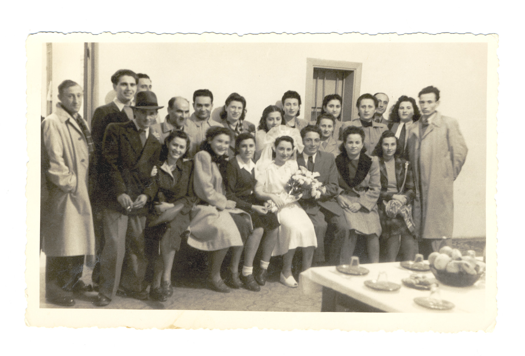 A recent immigrant couple poses on their wedding day surrounded by friends from an Italian displaced persons' camp and the illegal immigration ship, the Wingate.

Almost immediately after the wedding, the groom left to fight with the Haganna in the battles preceding the War of Independence.

Pictured in the center or Josef Fischer and his bride, Miraim Domawaska Fischer.  Next to Miriam is her sister Rivke Domawaska.  Next to Josef is Malka Yevelewicz who survived as a partisan.