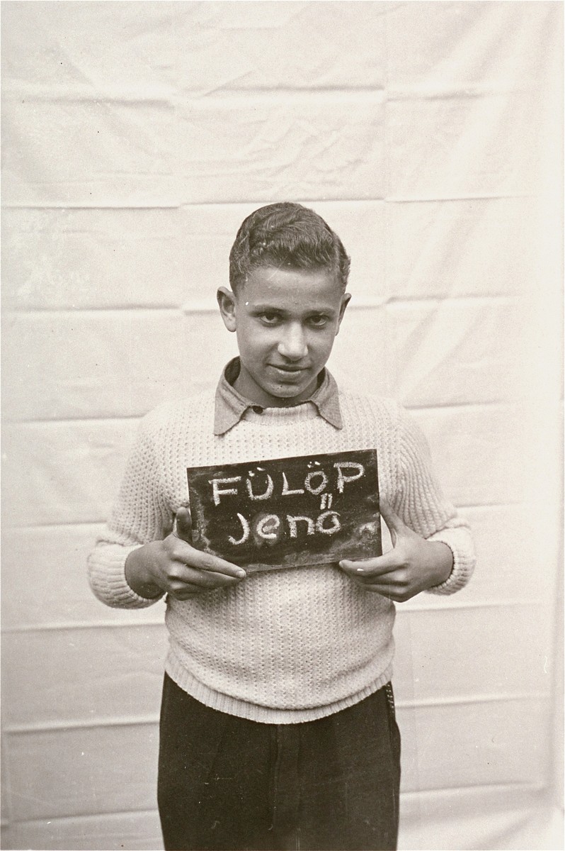 Jeno Fulop holds a name card intended to help any of his surviving family members locate him at the Kloster Indersdorf DP camp.  This photograph was published in newspapers to facilitate reuniting the family.