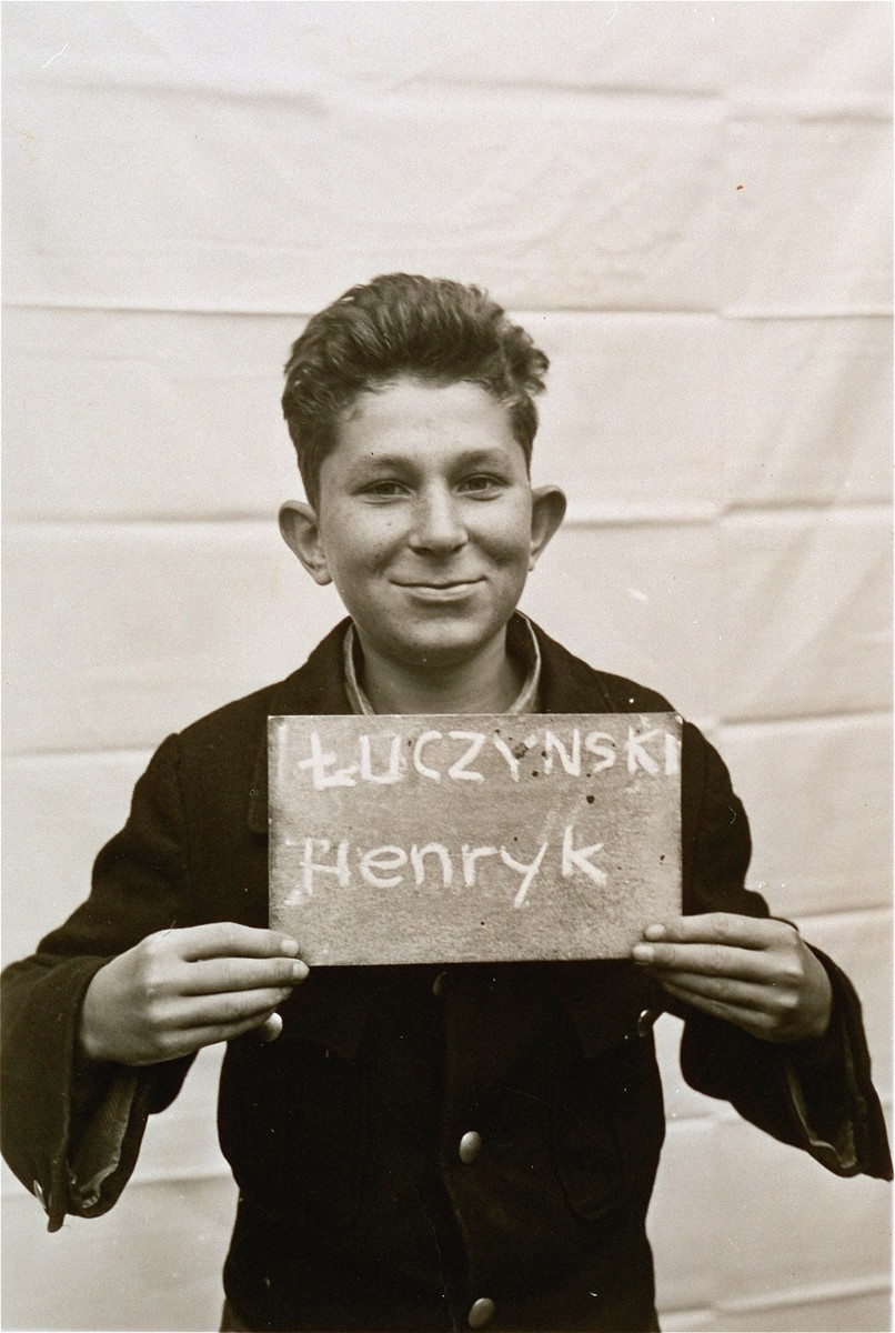 Henryk Luczynski holds a name card intended to help any of his surviving family members locate him at the Kloster Indersdorf DP camp.  This photograph was published in newspapers to facilitate reuniting the family.