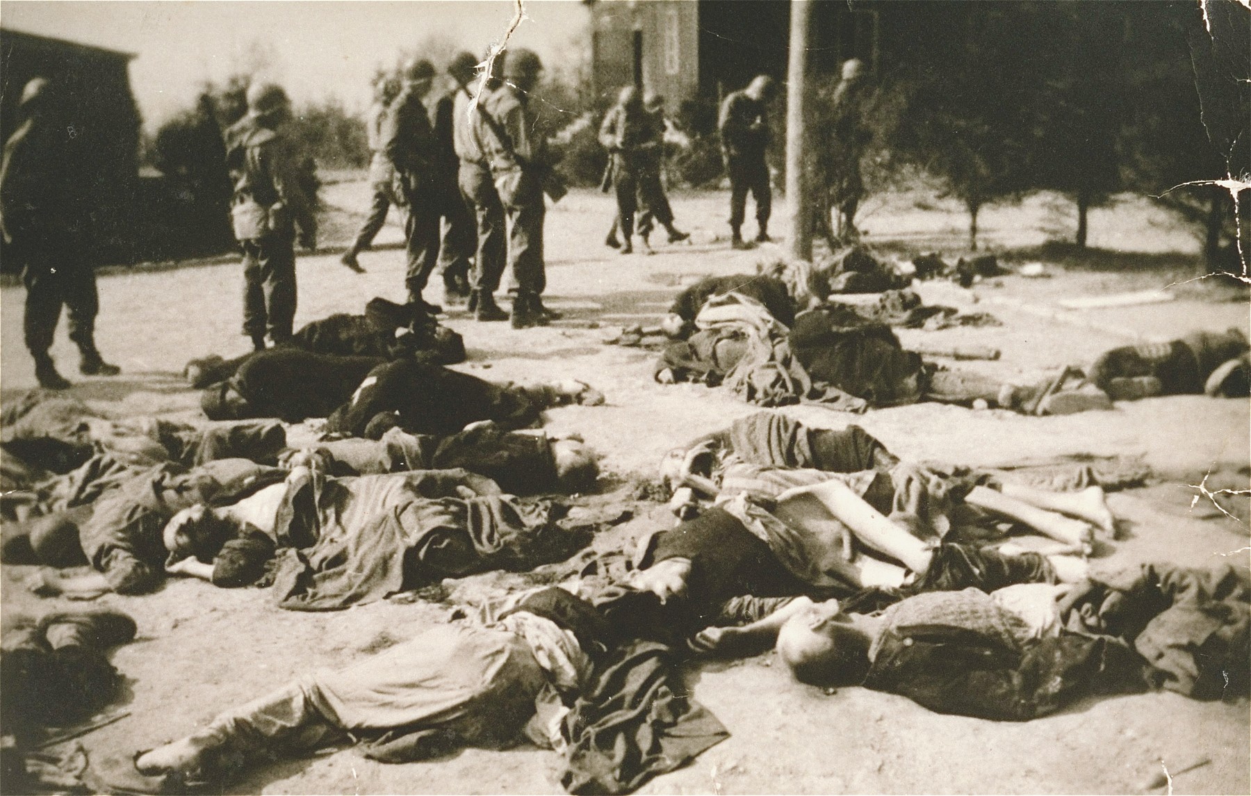 American soldiers walk past the bodies of Ohrdruf prisoners who were killed during the evacuation of the concentration camp.