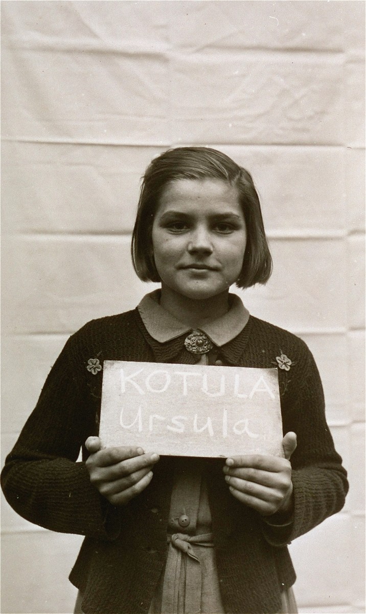 Ursula Kotula holds a name card intended to help any of her surviving family members locate her at the Kloster Indersdorf DP camp.  This photograph was published in newspapers to facilitate reuniting the family.