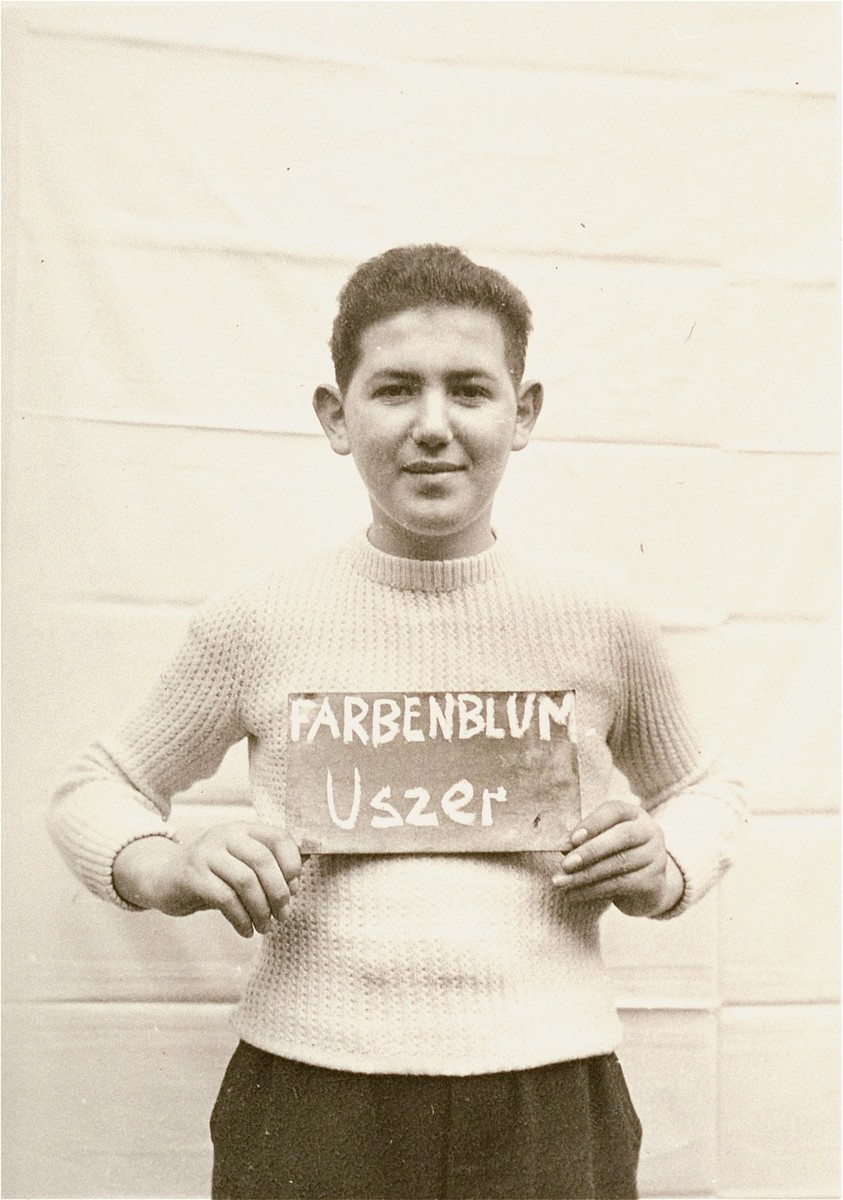 Uszer Farbenblum holds a name card intended to help any of his surviving family members locate him at the Kloster Indersdorf DP camp.  This photograph was published in newspapers to facilitate reuniting the family.