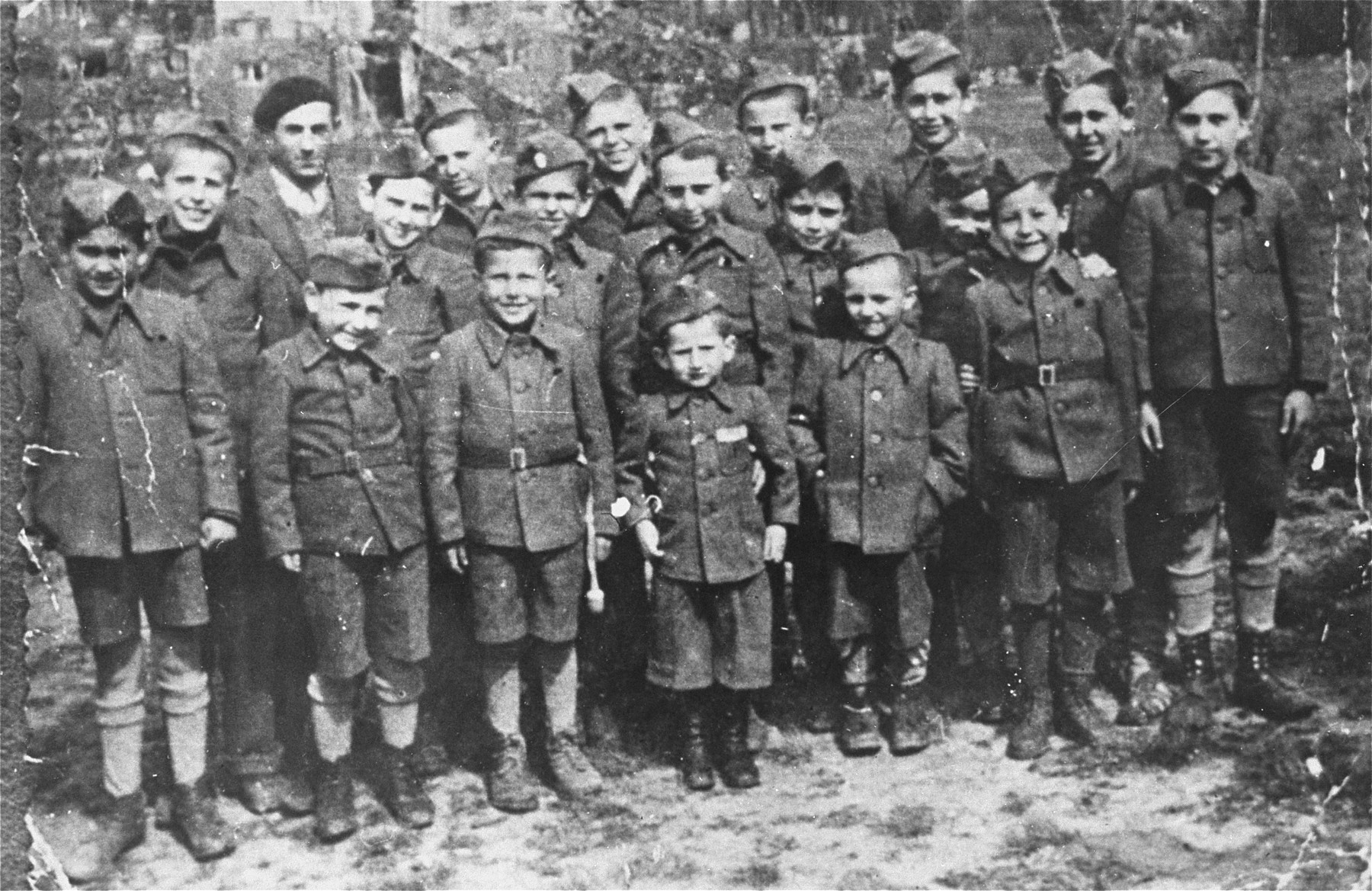 Group portrait of child survivors of the Buchenwald concentration camp.  

The boys are dressed in outfits made from German uniforms due to a clothing shortage.  Among those pictured are first row (left to right): Lolek Blum, David Perlmutter, Birenbaum, Joseph Schleifstein,  unidentified, and Israel Meir Lau (middle row, far right).  Middle row: Nathan Szwarc, Jack Neeman, Berek Silber, Jacques Finkel, unidentified, Marek Milstein, and Salek Finkelsztein.  Back row: Elek Grinbaum [or Grinberg], Chaim Finkelstajn [or Charles Finkel], Romek Wekselman [or Wajsman], and Abram Czapnik.