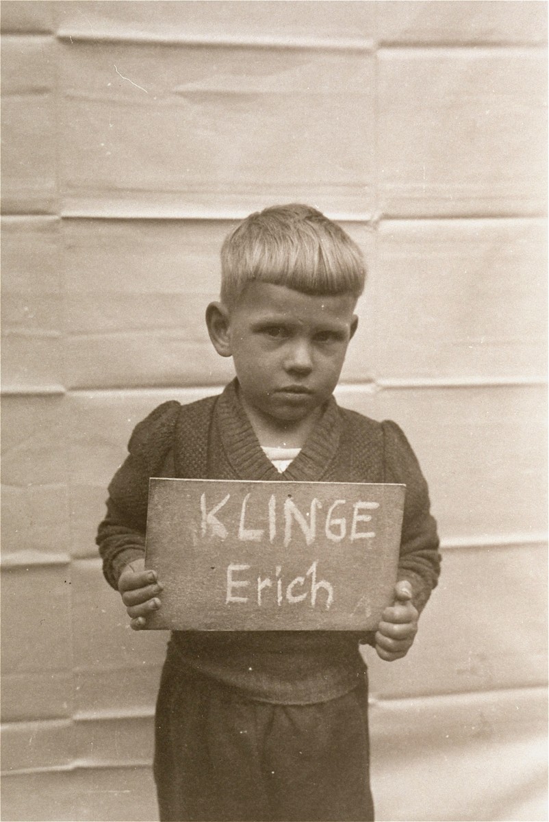 Erich Klinge holds a name card intended to help any of his surviving family members locate him at the Kloster Indersdorf DP camp.  This photograph was published in newspapers to facilitate reuniting the family.