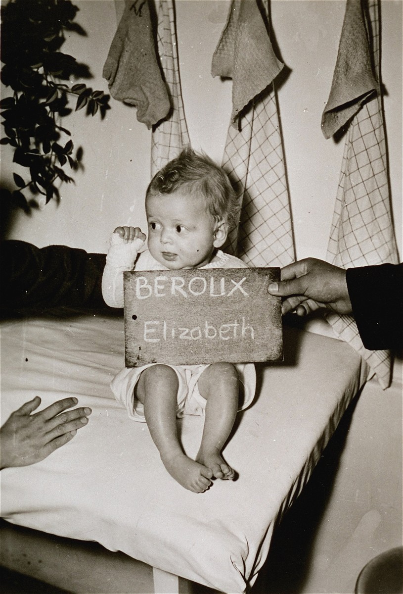 Elizabeth Beroux with a name card intended to help any of her surviving family members locate her at the Kloster Indersdorf DP camp.  This photograph was published in newspapers to facilitate reuniting the family.