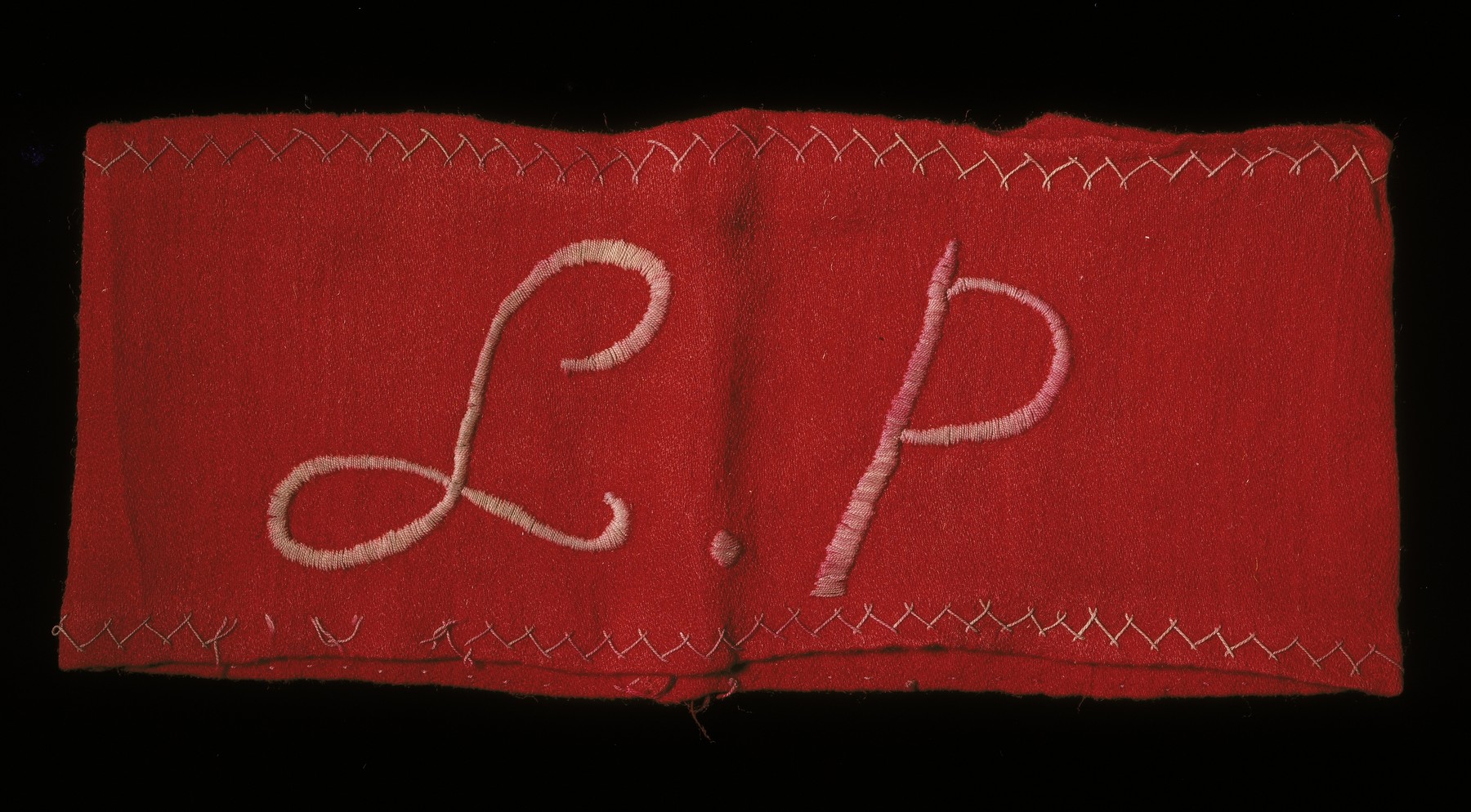 An armband stitched with the initials "L.P." Lager Polizei (camp police).