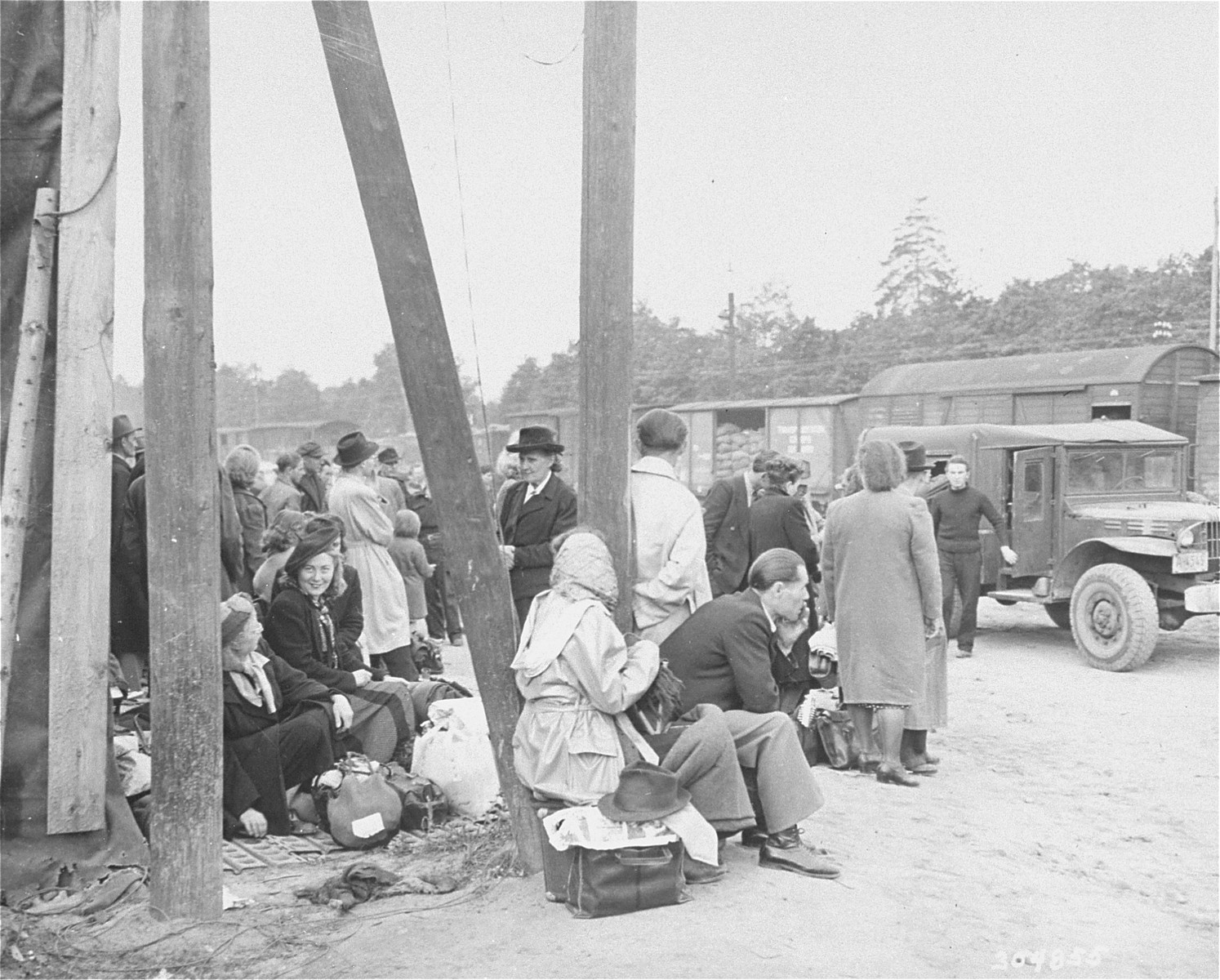 Jewish DPs who have been evacuated from Berlin to Frankfurt as a result of the Soviet blockade, wait at the Rhine Main Airfield for transport to displaced persons camps.

The original caption reads, "Jewish displaced persons arrive by plane at the Rhine Main Airfield, Frankfurt, Germany, from the blockaded city of Berlin, on operation "Vittles". 150 came in the first group, and 180 are expected to arrive on July 24, 1948. Most of these DPs have been granted visas by the new State of Israel, and will go to DP camps in the U.S. zone to await shipment to Palestine, while others will leave for Canada, France and the U.S.. Here DPs wait for trucks to arrive to carry them to trains."