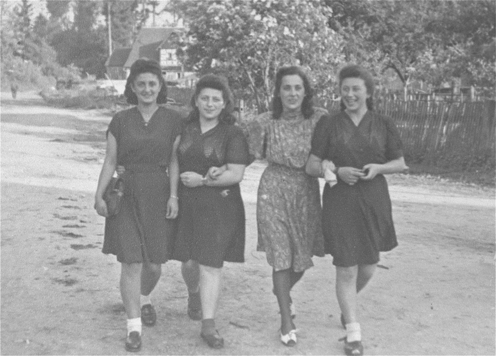 Four young Jewish women who were recently liberated from the Schatzlar labor camp, walk arm-in-arm along a road.

Pictured from left to right are: unknown, Herscovicz (from Sosnowiec), Gusta Fiszgrund (from Crzanow), and Pola Herscovicz (from Sosnowiec).