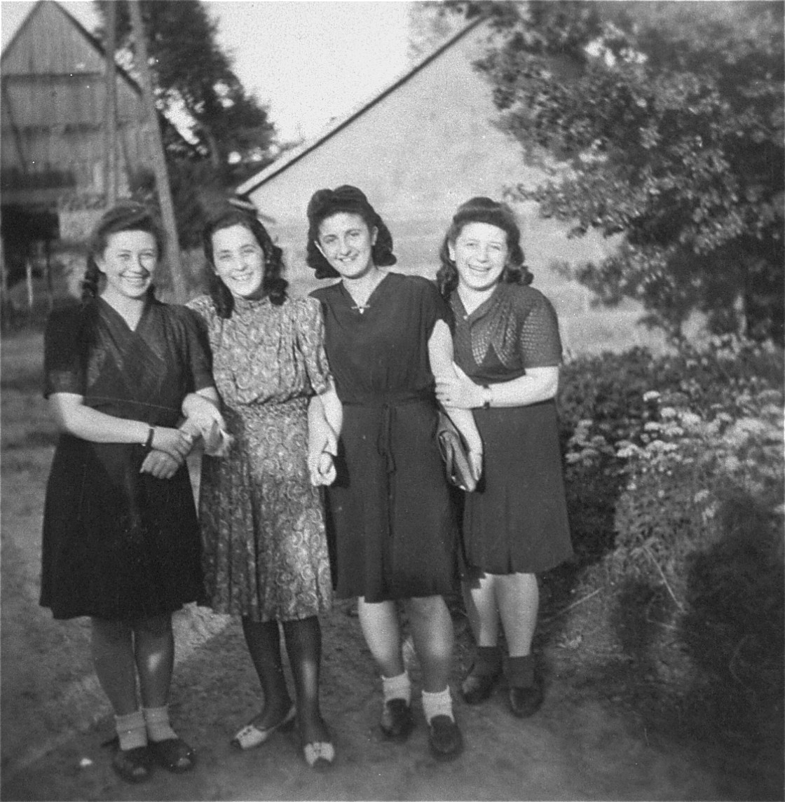 Four young Jewish women who were recently liberated from the Schatzlar labor camp, pose outside in front of a group of buildings.

Pictured from left to right are:  Pola Herscovicz (from Sosnowiec), Gusta Fiszgrund (from Crzanow), unknown, and Herscovicz (from Sosnowiec).