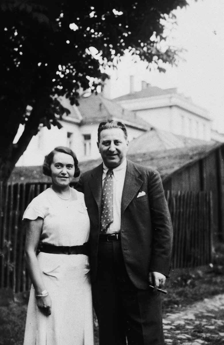 A Jewish couple pose on a garden path next to a fence.

Pictured are Esti and Bela Weichherz.

This photo was taken from the diary of Kitty's life written by her father, Bela Weichherz.