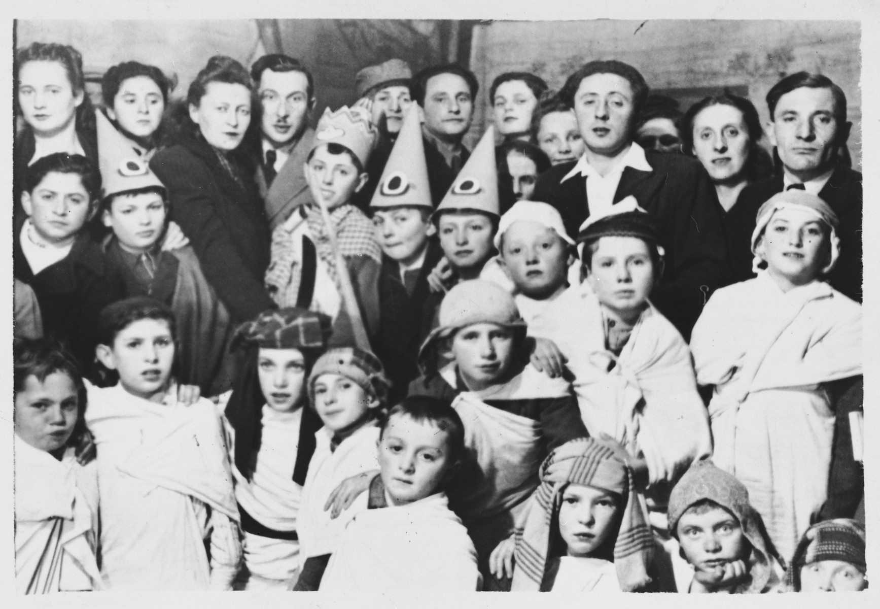 Children attend a Purim costume party in the Foehrenwald DP camp.

Those pictured include Chaim Swidler, Roman Haar and Barry Golub.  The principal Mr. Biber is on the right, and a teacher Mr. Zektzer is in the second row on the far left.