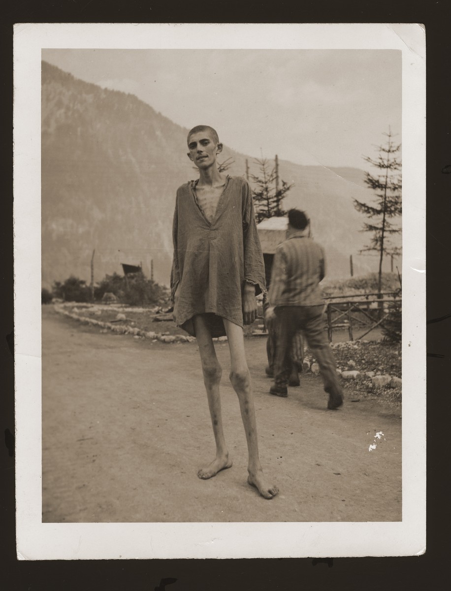 An emaciated survivor poses on a road in the Ebensee concentration camp two days after his liberation.

This survivor, who spoke English, served as a guide and translator for US Army Signal Corps photographer Arnold Samuelson during his two days at the concentration camp.