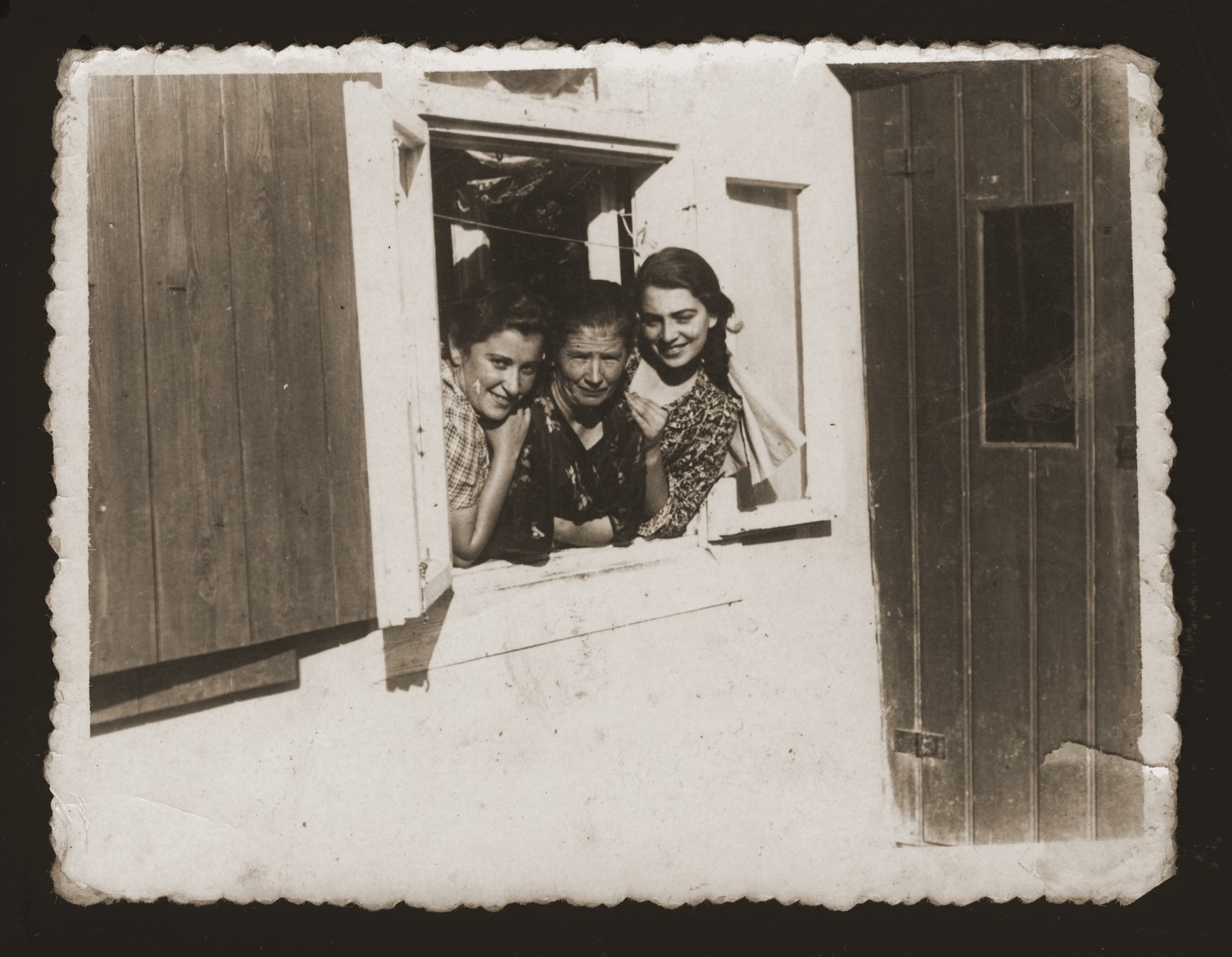 Three Jewish women look out the window of a house in Maciejow.

Among those pictured is Estera Ajzen (right) during a visit to her friend's home.