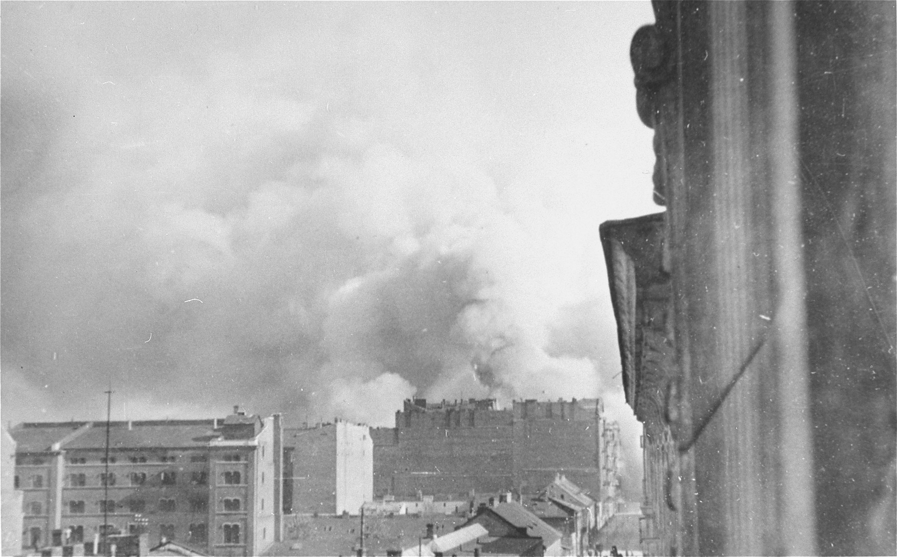 Smoke rises from buildings razed by the SS during the suppression of the Warsaw ghetto uprising.  The view is from Walicow Street looking south.
