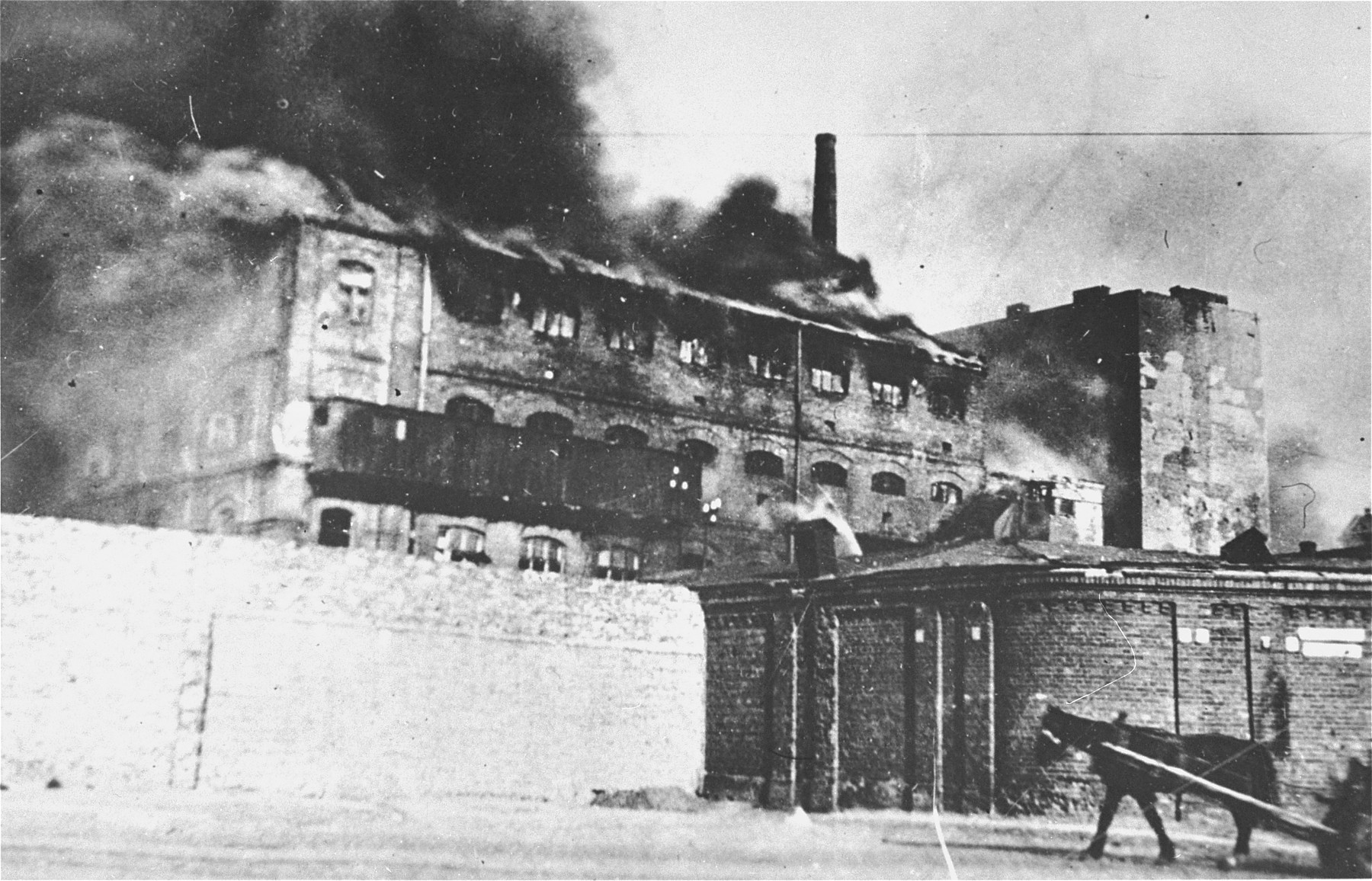 A factory razed by the SS burns during the suppression of the Warsaw ghetto uprising.