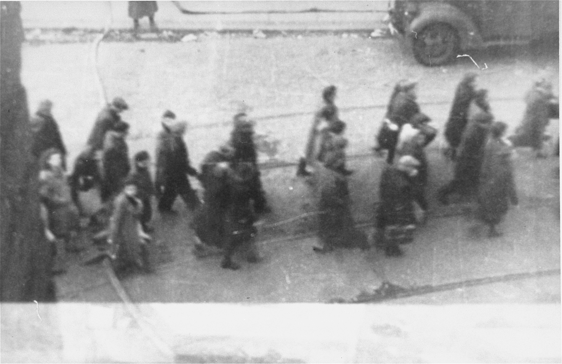 Jews captured by the SS during the suppression of the Warsaw ghetto uprising march past the St. Zofia hospital down Nowolipie Street towards the Umschlagplatz for deportation.