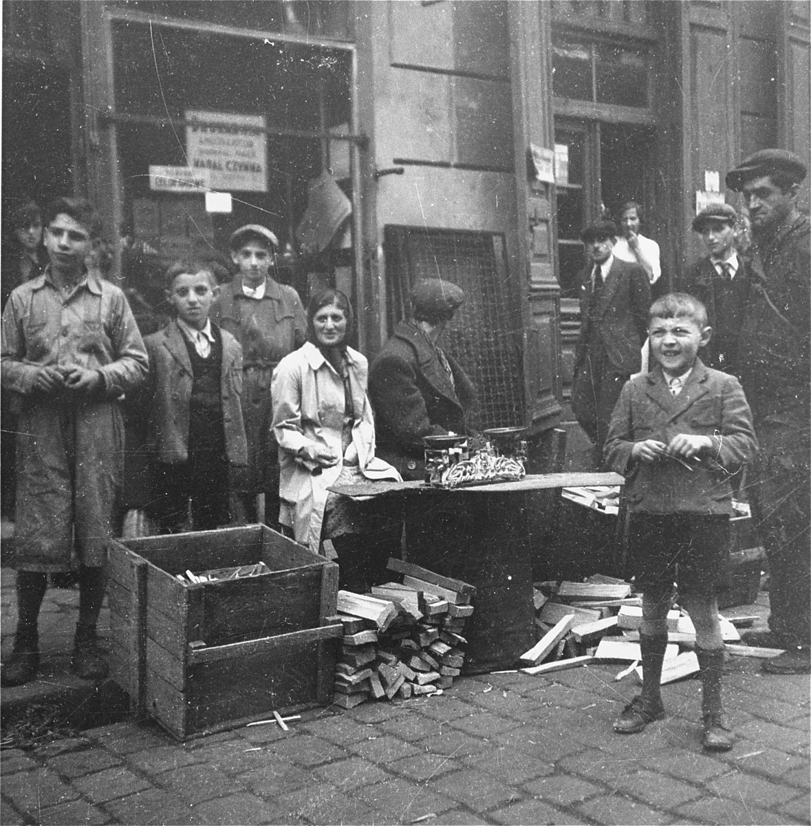 Vendors sell blocks of wood and kindling on the street in the Warsaw ghetto.  

Joest's original caption reads: "Both of these vendors weighed pieces of wood and kindling with a kitchen scale.  Truly, with the scale!"