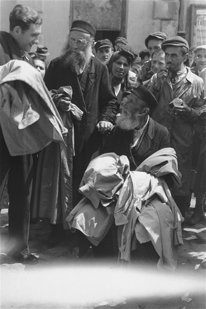 A street vendor selling overcoats haggles with a customer at an open air market in the Warsaw ghetto.