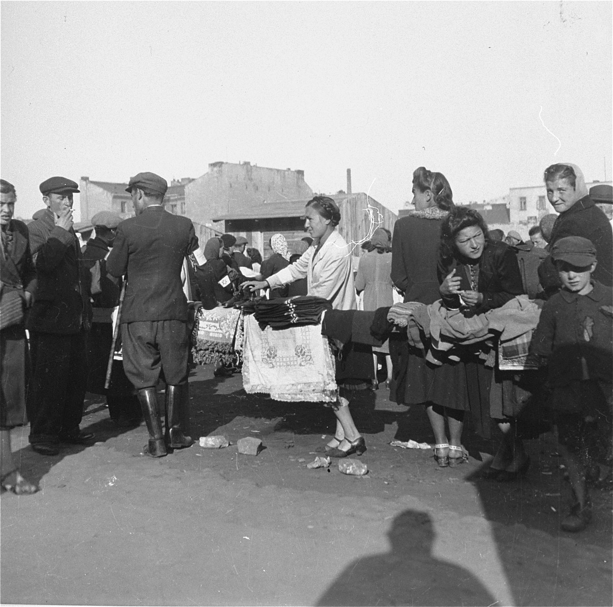 Inhabitants of the Warsaw ghetto offer household goods and clothing for sale at an open air market. 

Joest's original caption reads: "One could buy rugs, handkerchiefs, socks, hats, and skirts on the black market.  The Jews sold off their household items so they could survive."