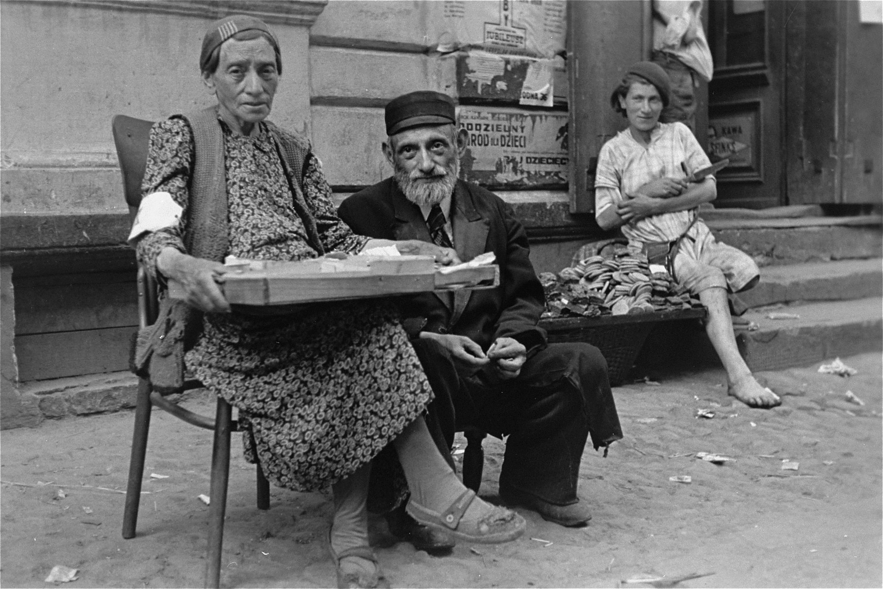 An elderly couple sells goods on the street in the Warsaw ghetto.
