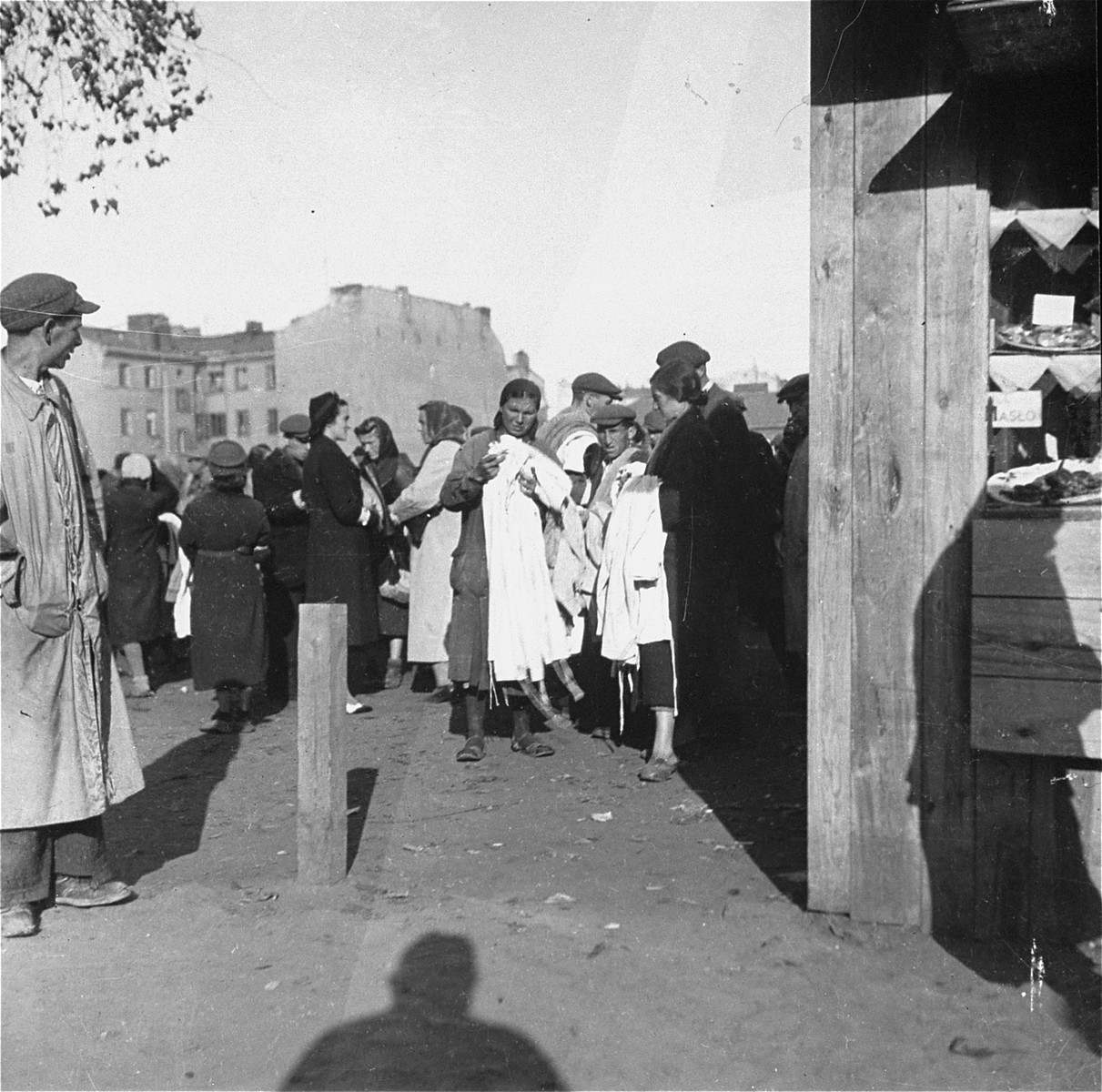Inhabitants of the Warsaw ghetto sell clothing to Polish customers at an open air market.  

Joest's original caption reads: "Those with the white armbands, the Jews, were the ones selling.  Those without armbands, the Poles, were the buyers."