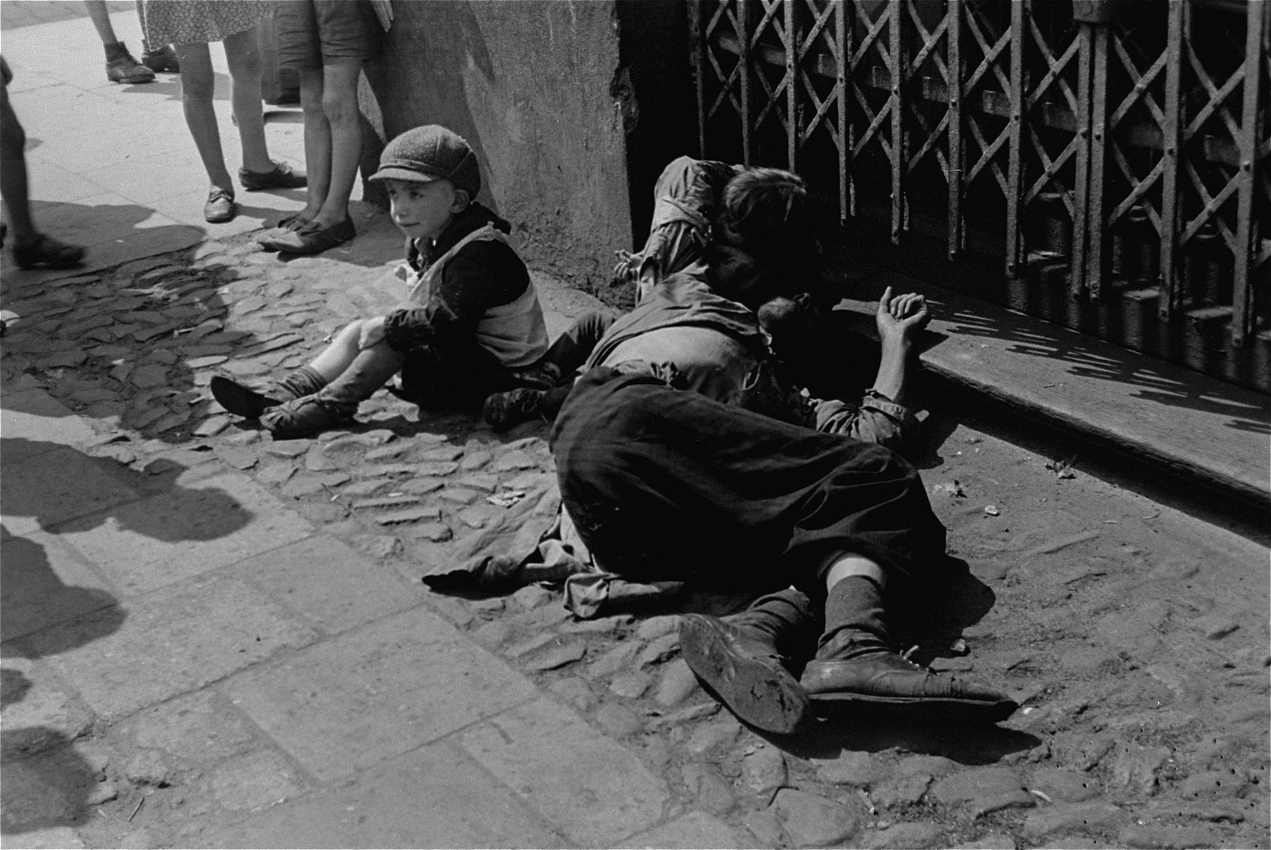 A destitute father and his two children sit on the street in the Warsaw ghetto.