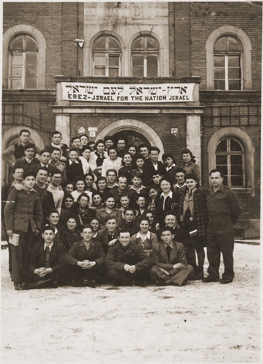 Group portrait of Jewish DPs in Deggendorf, Germany posing under a Zionist banner which reads, "Eretz Israel [the Land of Israel] for the Nation Israel," in Hebrew and English.

Seated on the far left is William Loew.