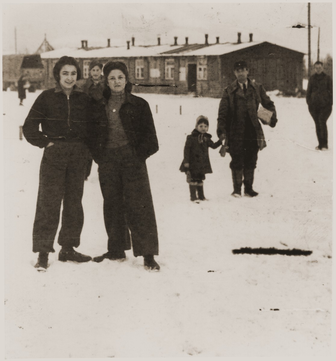 Helen Verblunsky stands with a friend in the snow outside the barracks of an unidentified DP camp in the British zone.