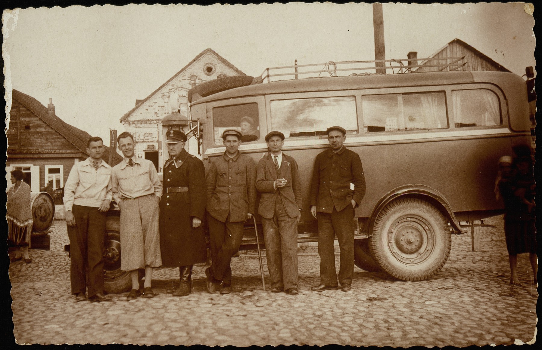 Bus drivers and gas station owners stand next to a bus parked by the shtetl's gas station and bus stop.

(left to right) Moshe Slonimski; Israel Erlich; Avraham Krisilov; a local Polish policemen; and two bus drivers.  Slonimski and Krisilow were co-owners of the Shell Oil station.  Both were murdered by the Germans during the September 1941 mass shooting action.  Israel Erlich was killed by the AK.
