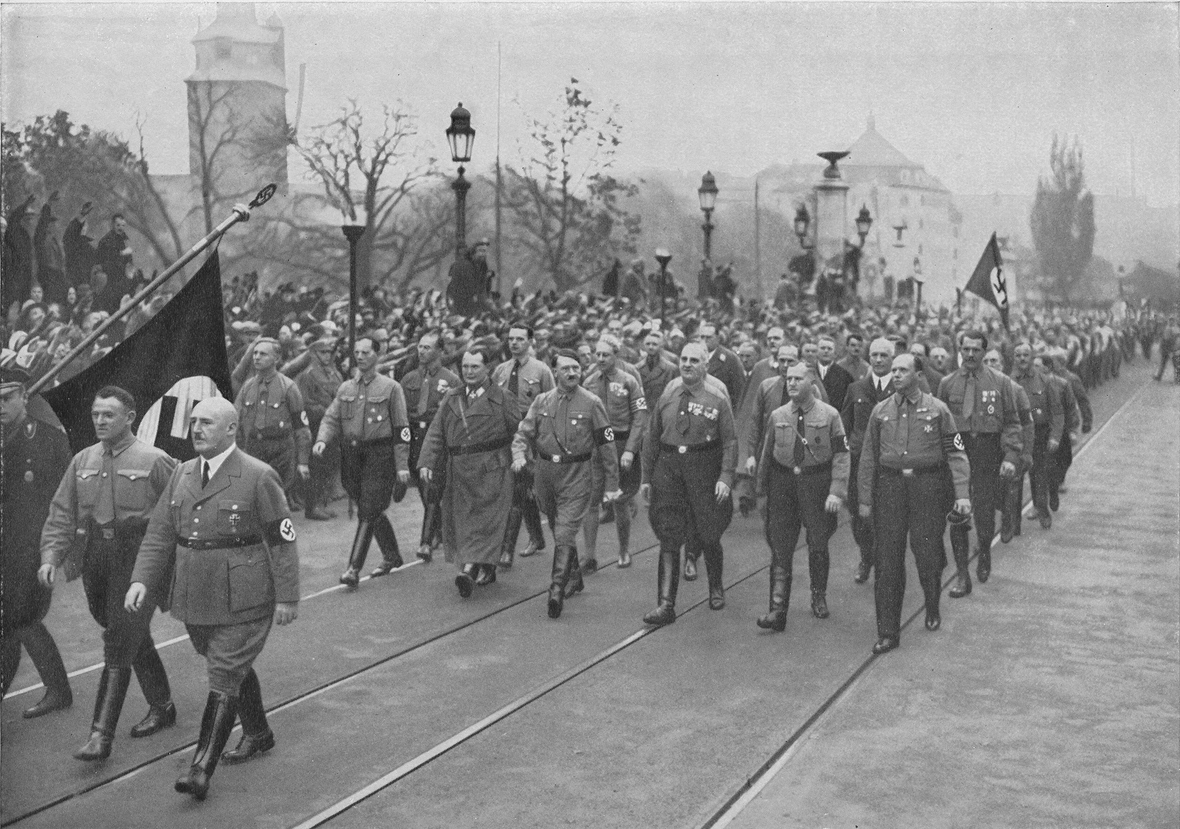 Adolf Hitler (center, front row) and Hermann Goering (third from left, front row) lead a march through the streets of Munich to commemorate the November 8-9, 1923 Beer Hall Putsch. Julius Streicher marches with the Nazi colors (lower left corner, third from left).