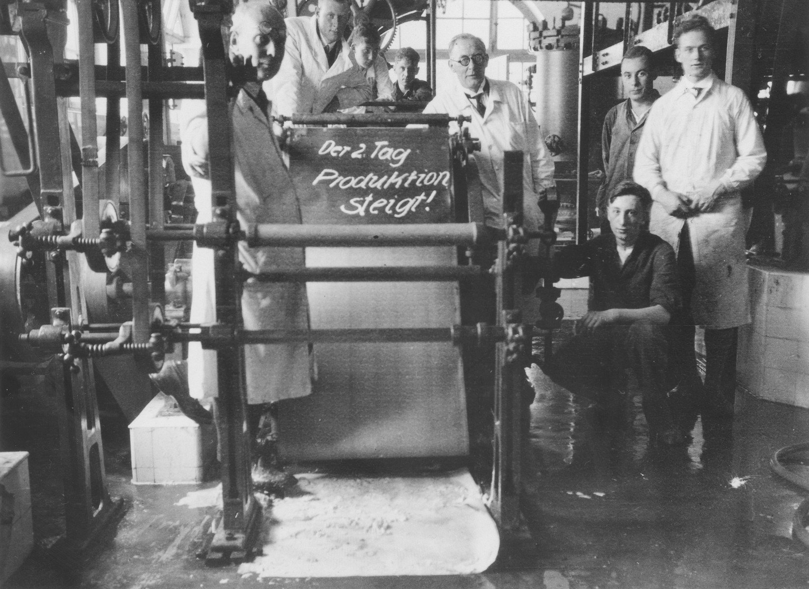 Herbert Mosheim (kneeling) poses in a factory where he is working as an apprentice while attending engineering school.