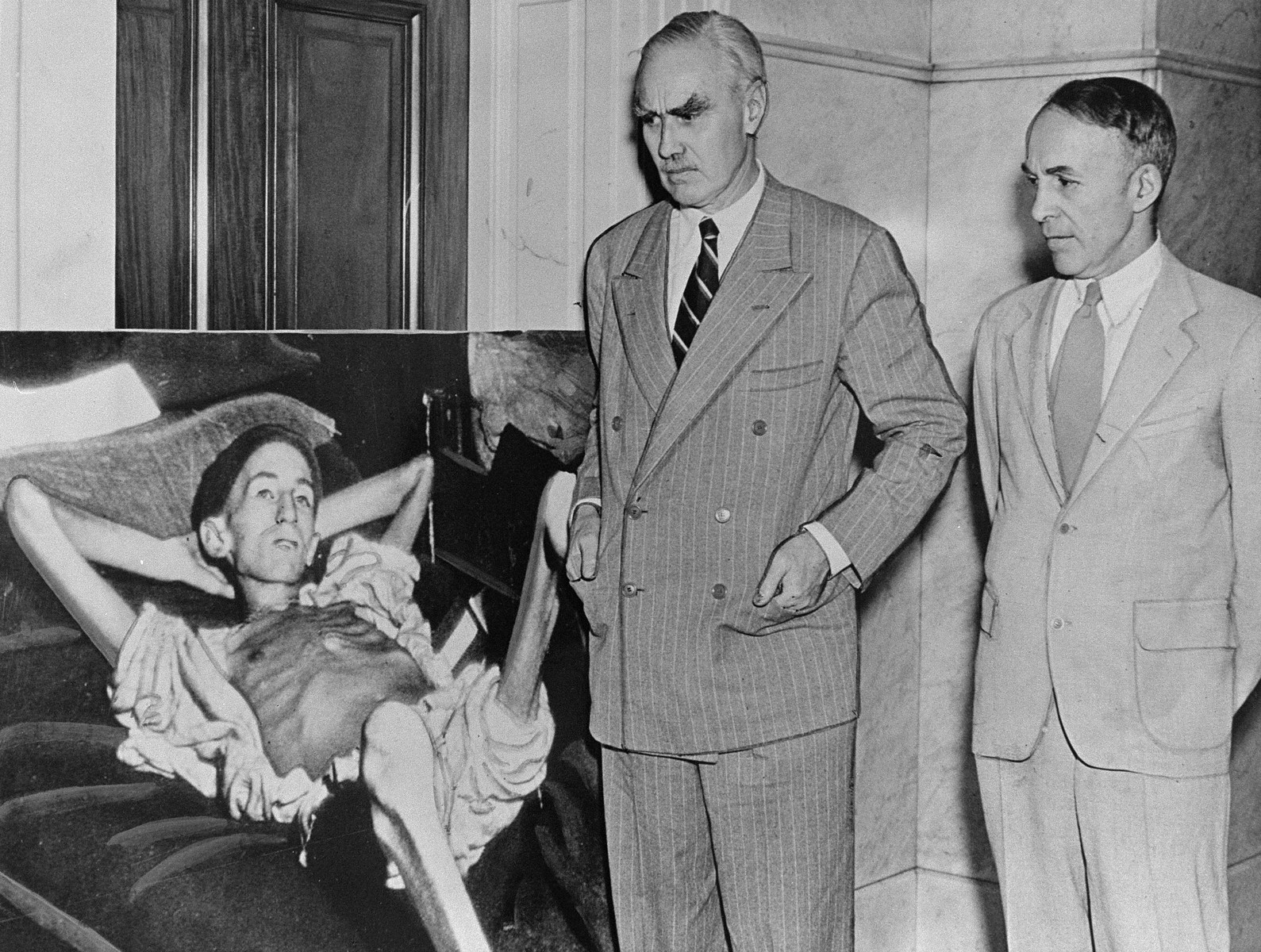 Visitors view a photomural of an emaciated concentration camp survivor at the "Lest We Forget" exhibition at the Library of Congress.