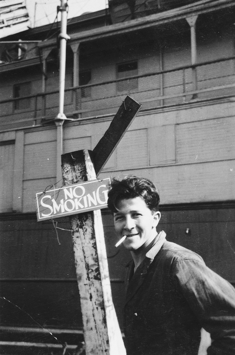 Itzhak Aronowitz, chief mate and later captain of the President Warfield (later the Exodus 1947), lights up a cigarette in front of a "no smoking" sign in Baltimore harbor.