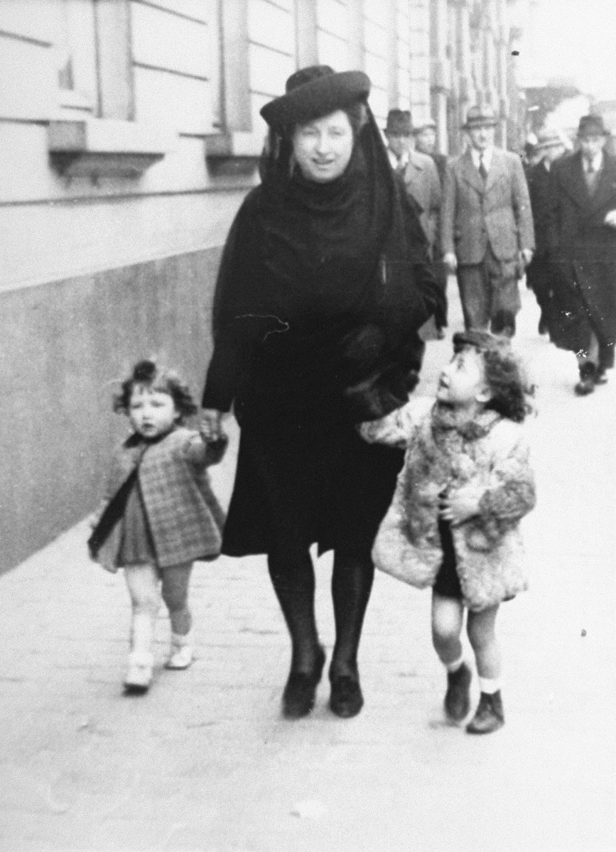 Margo and Annette Lederman, two Jewish children in hiding, walk along a street in Rumst, Belgium with their rescuer, Clementine van Buggenhout.