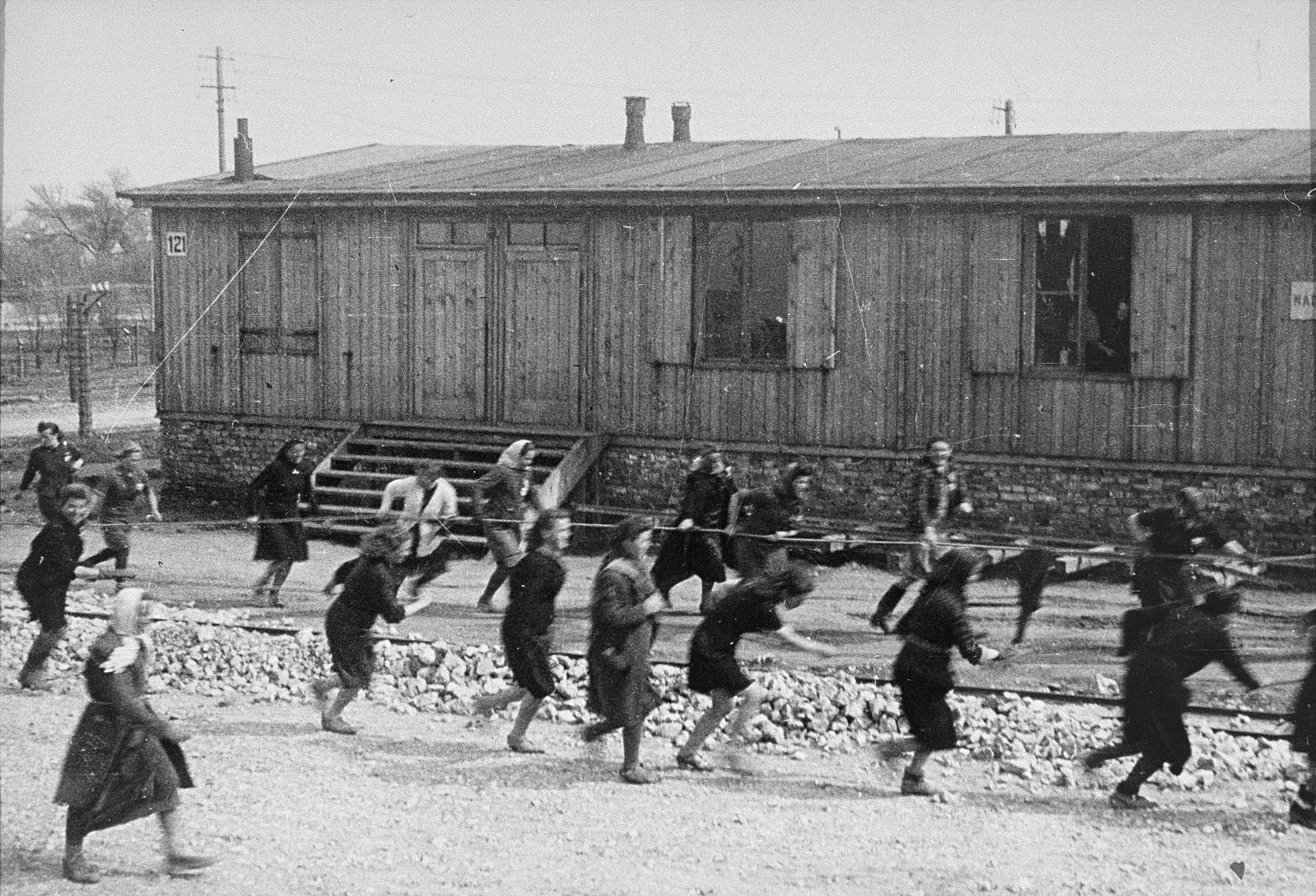 Jewish women at forced labor in Plaszow.  

Behind them is barrack #121, which was owned by the clothing firm of J. Madritch of Vienna.  Its workshops on "Industry Street" in the camp were an independent organization within the DAW (German Arms Institution).