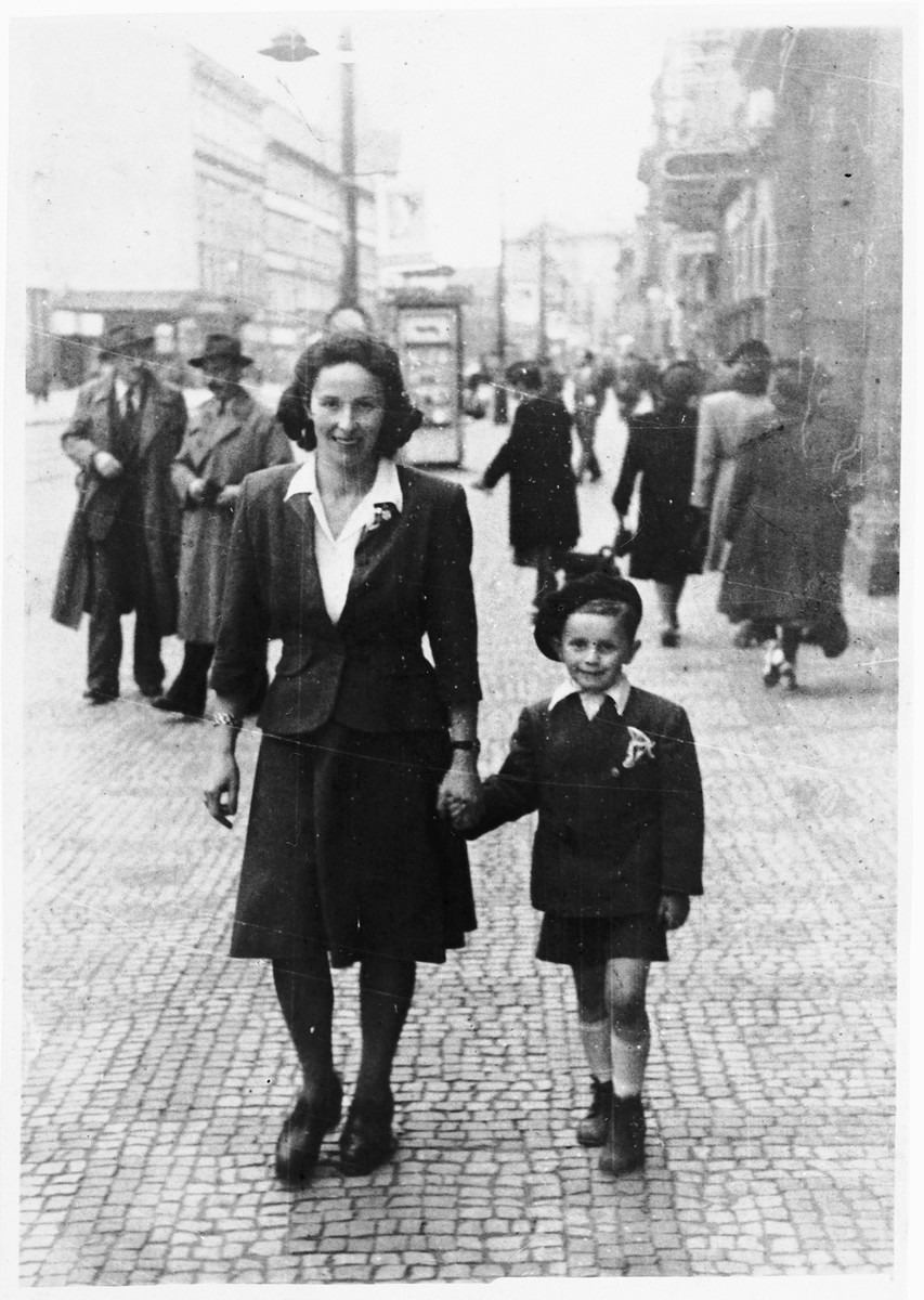 A Jewish woman walks down the street, hand in hand with her young son.

Pictured are Berte Akerman and Moshe Tomas.