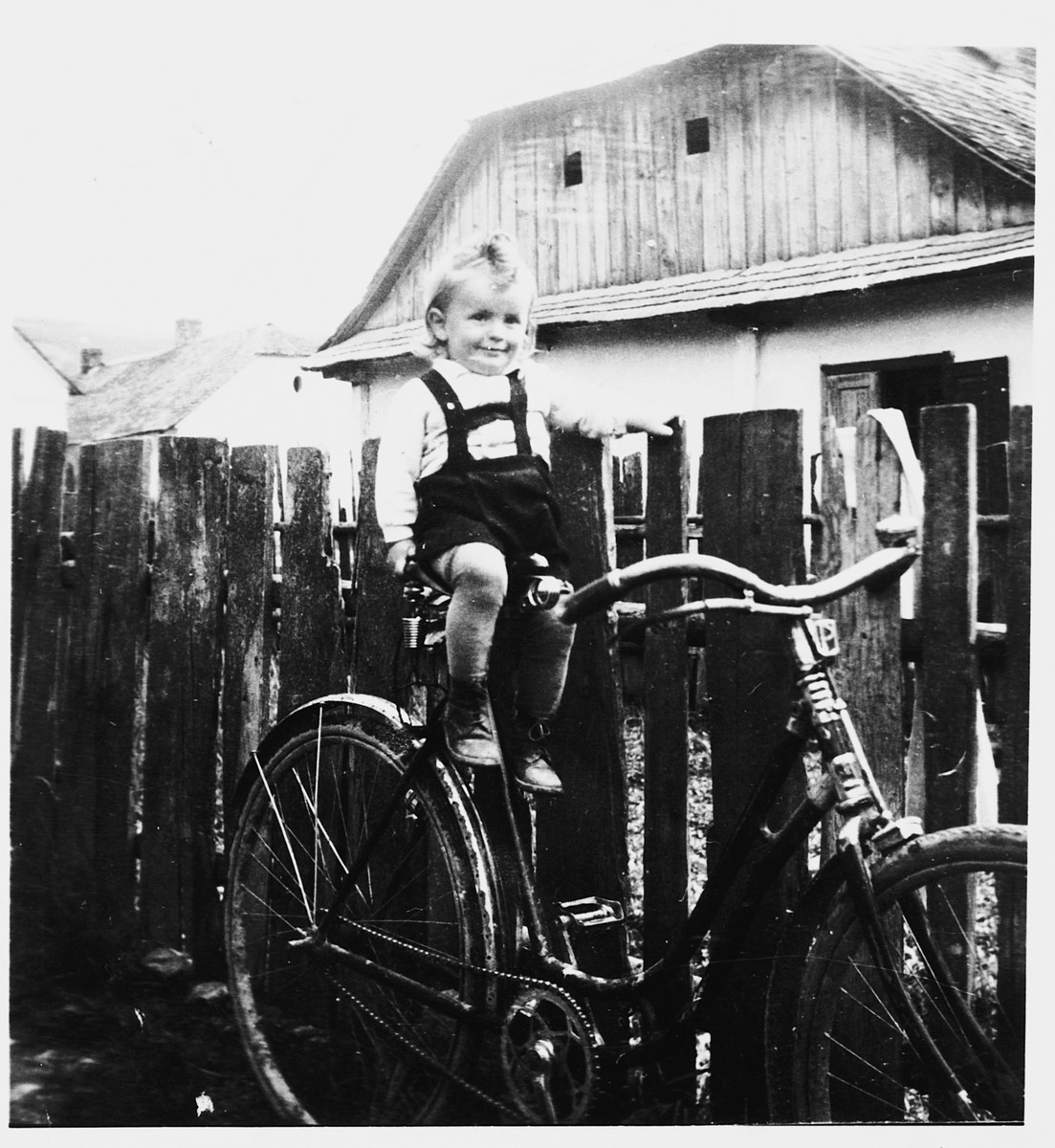 Moshe Thomas sitting on a bicycle near his grandmother's home in Nizni Verecky.